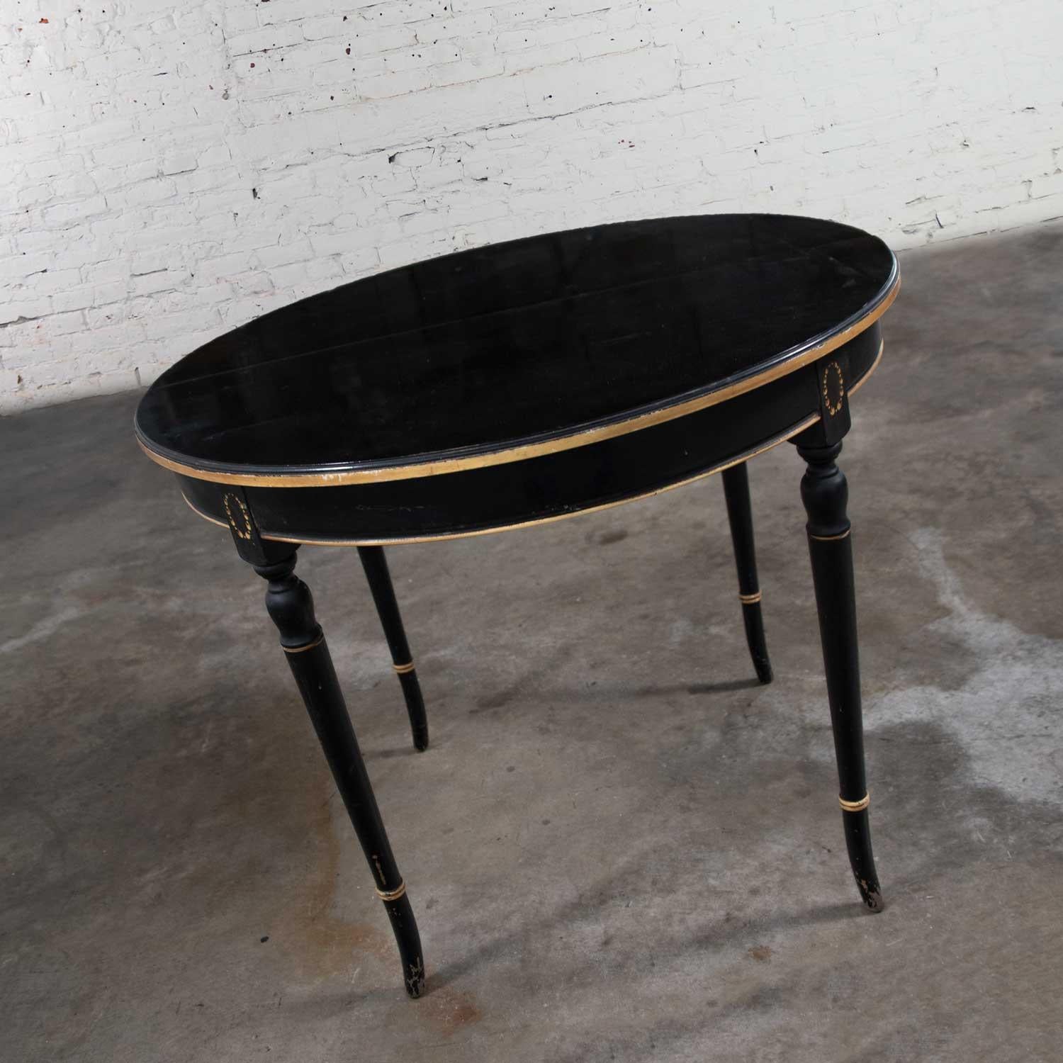 Handsome round neoclassical dining table or center table with its original black painted and perfectly age-distressed finish with gold painted details. It is in wonderful solid condition with a beautifully aged patina which includes wear to the