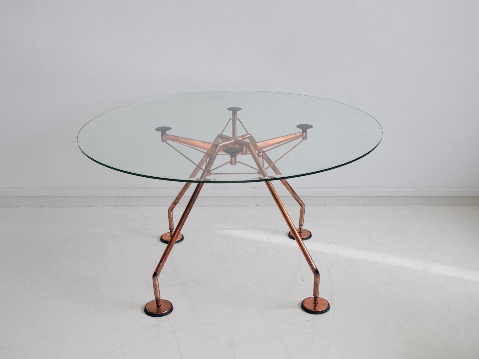 Dining table, model Nomos, design by Sir Norman Foster & Partner for Tecno, Italy. Designed in 1986. Filigree frame made of steel tube and aluminum, which has been renewed and bathed in copper. Loose clear glass plate.