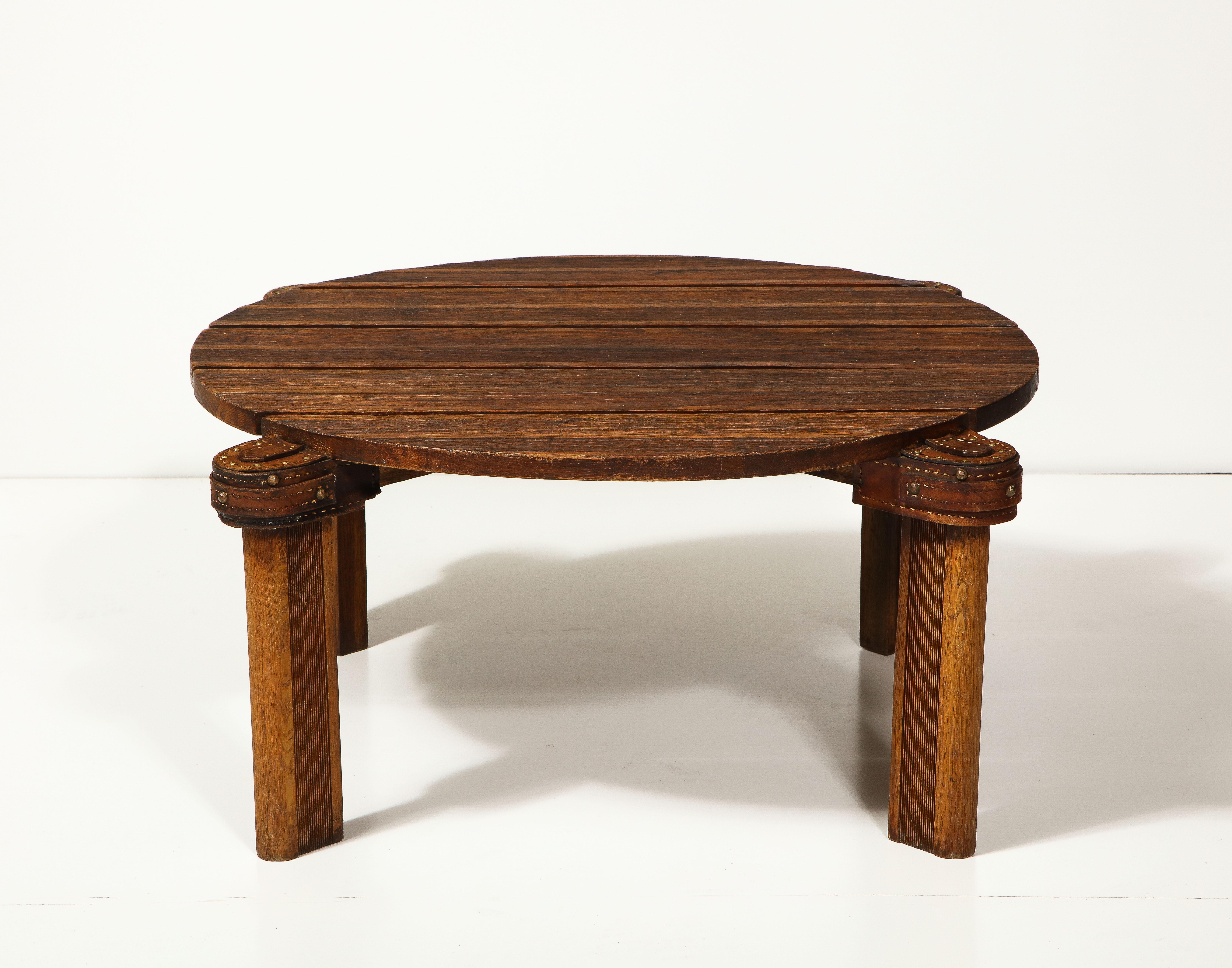 Round oak and leather coffee table by Jacques Adnet, France, c. mid-20th century 

This simple yet sophisticated table consists of reeded legs, a slatted plank top, and handsome stitched leather details typical of Adnet.