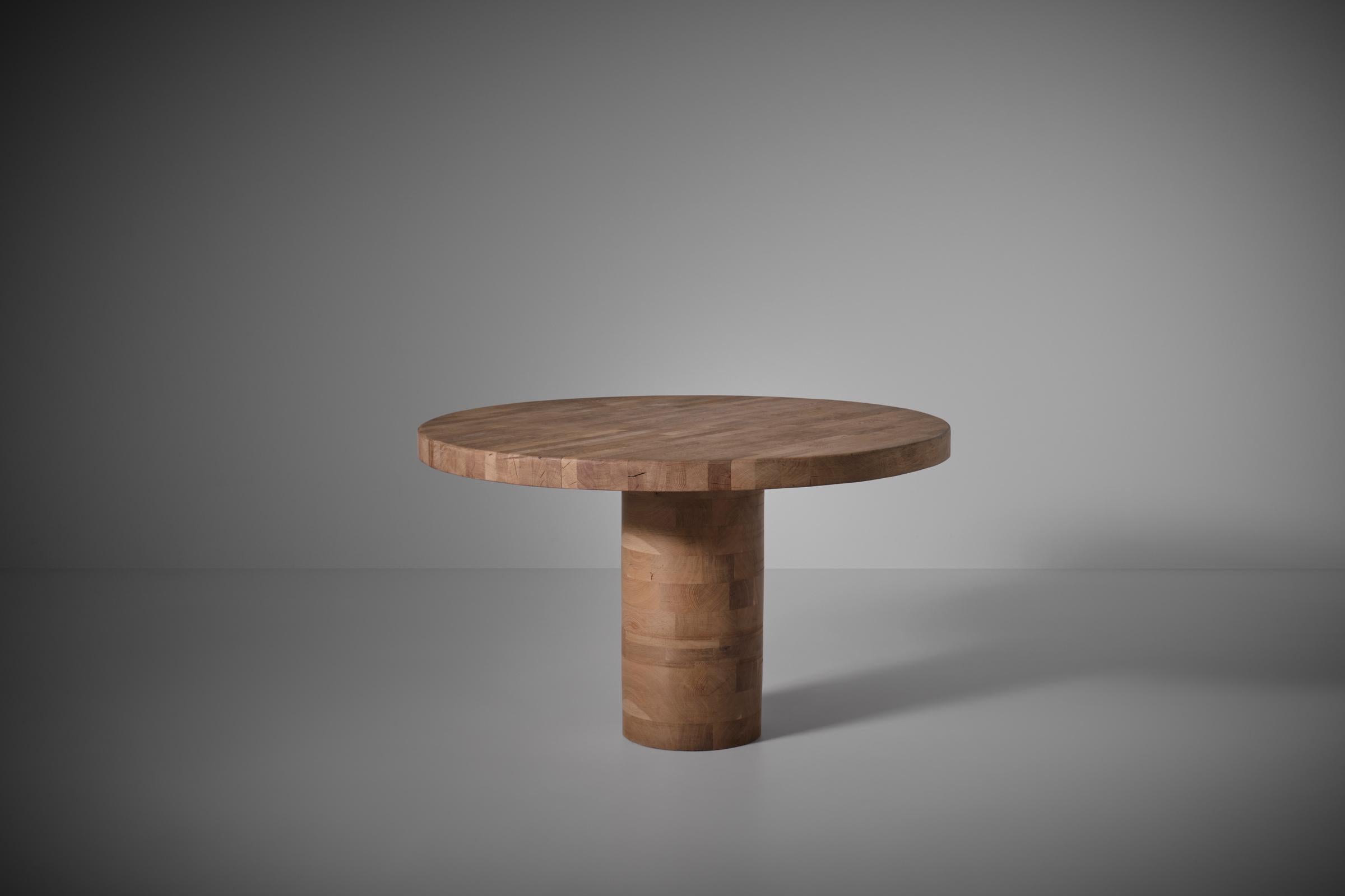 Round Oak dining table with cylinder base, 1970s. Heavy 7 cm thick round top constructed from different slats of solid oak, creating a beautiful pattern. The top is mounted on a cylinder shaped base made from different layers of solid Oak, resulting