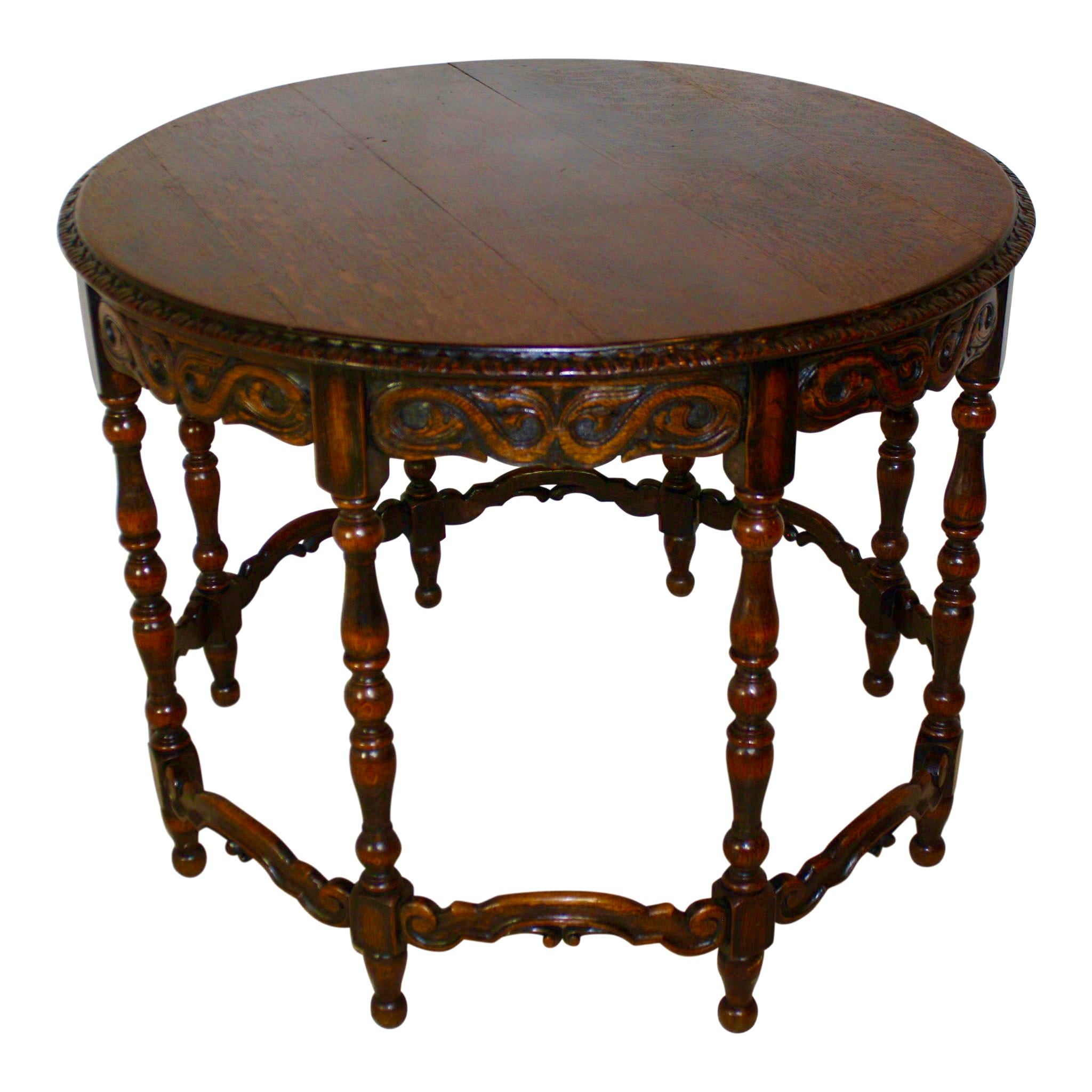 Eight turned legs with ball feet are gracefully connected by carved, ached stretchers, providing stylish support to this round table. The apron beneath the tables carved and beveled edge features opposing S-scrolls, which terminate in acanthus
