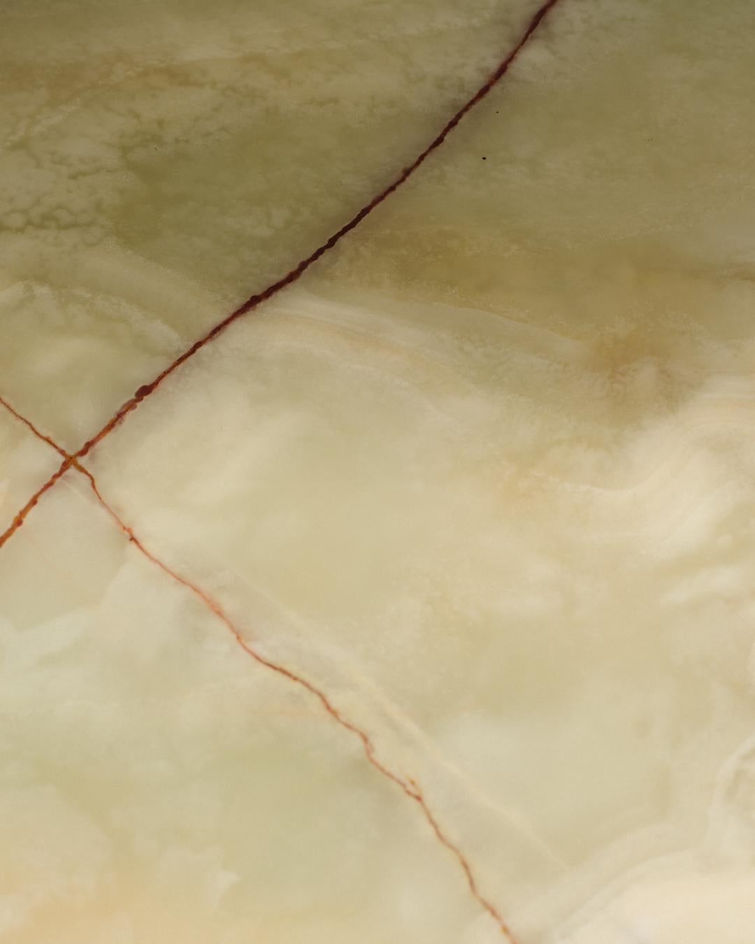 Table basse ronde des années 1960, plateau amovible en onyx beige nuancé de vert, reposant sur un piètement métallique. Deux chocs importants à signaler sur le contour du plateau.
