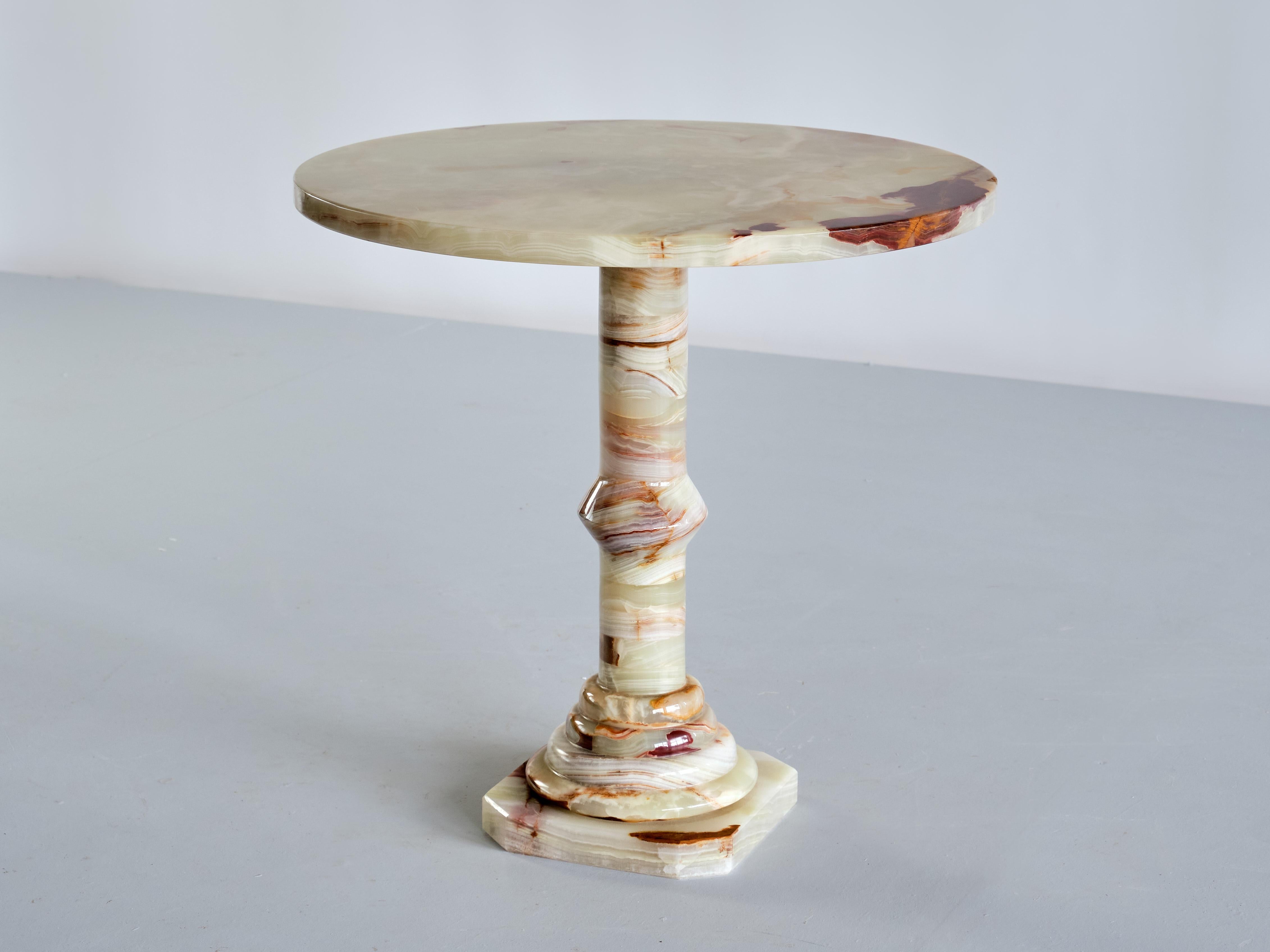 This elegant side table was produced in Italy in the 1960s. The pedestal base made of circular stacked discs and the round top are all made of solid multicolored onyx. The different hues and intensities of red, white and green give the table a