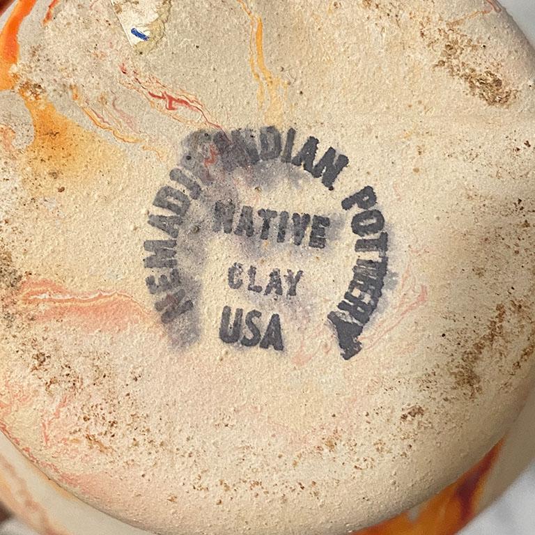 A midcentury style touring pottery piece. Its round base widens toward the body of the vessel and tapers inward toward the neck. Rich oranges are marbled throughout. 

Bottom reads:
Nemadji Indian Pottery
Native clay
USA

Dimensions:
5