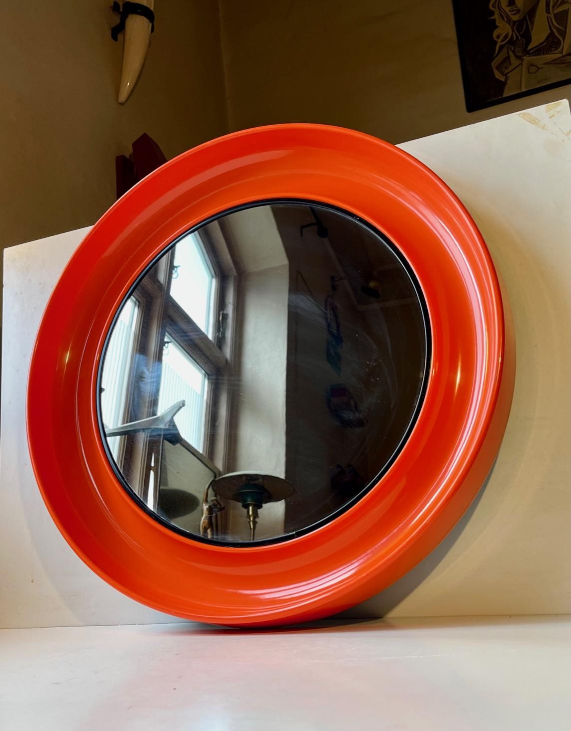 A circular wall mirror in molded orange plastic. Beautiful. organic lines and curves. Manufactured in Denmark during the 1970s by Termotex. Anonymous designer. It features a hidden wall mount for a single screw. Reminiscent in style to Verner Panton