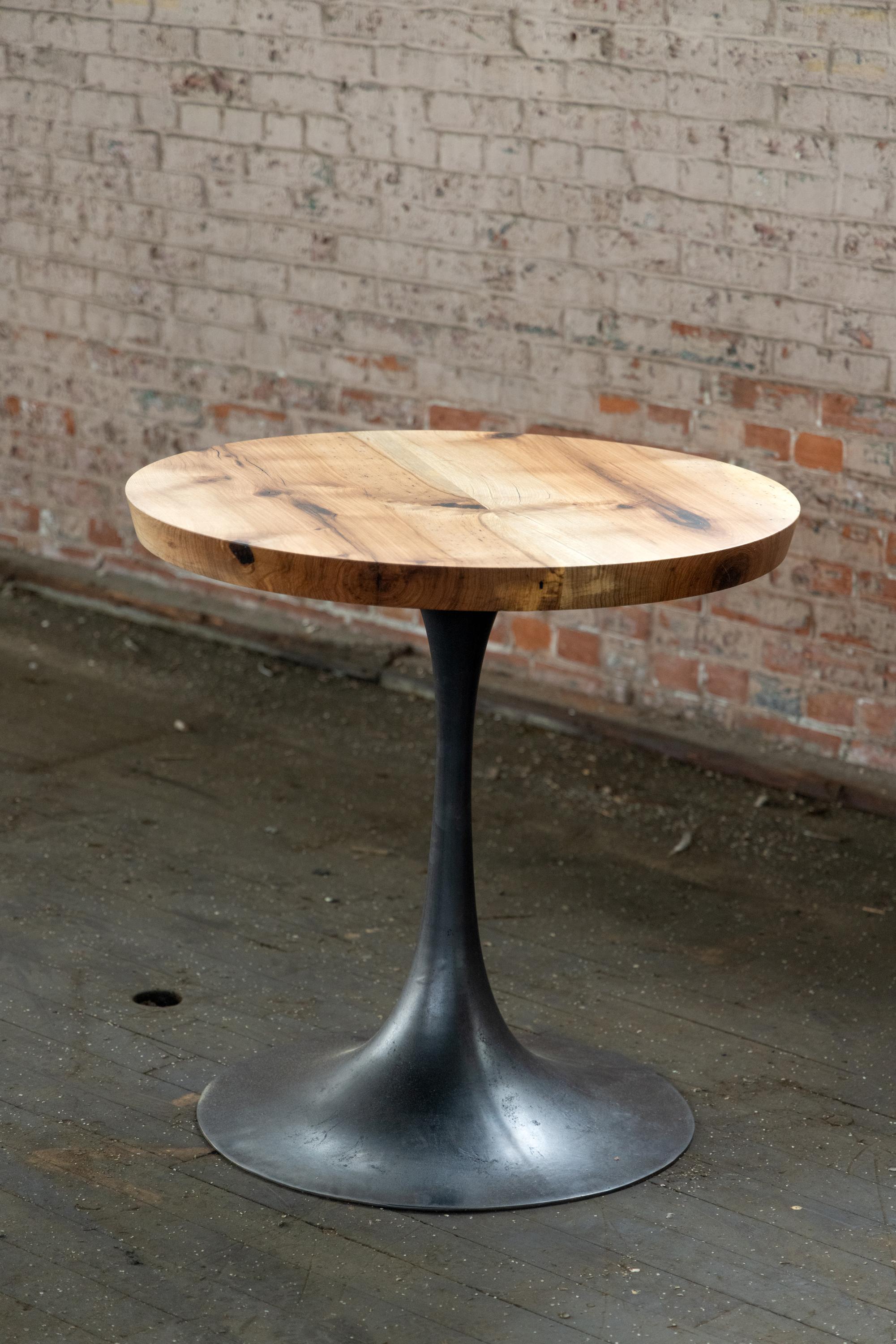 The Amicalola base captures the room set against a round or oval table top. This pedestal base is hand cast in bronze by local artisans, trained in the historic linage of steel in Birmingham, to look beautiful and function out of the way of diner's