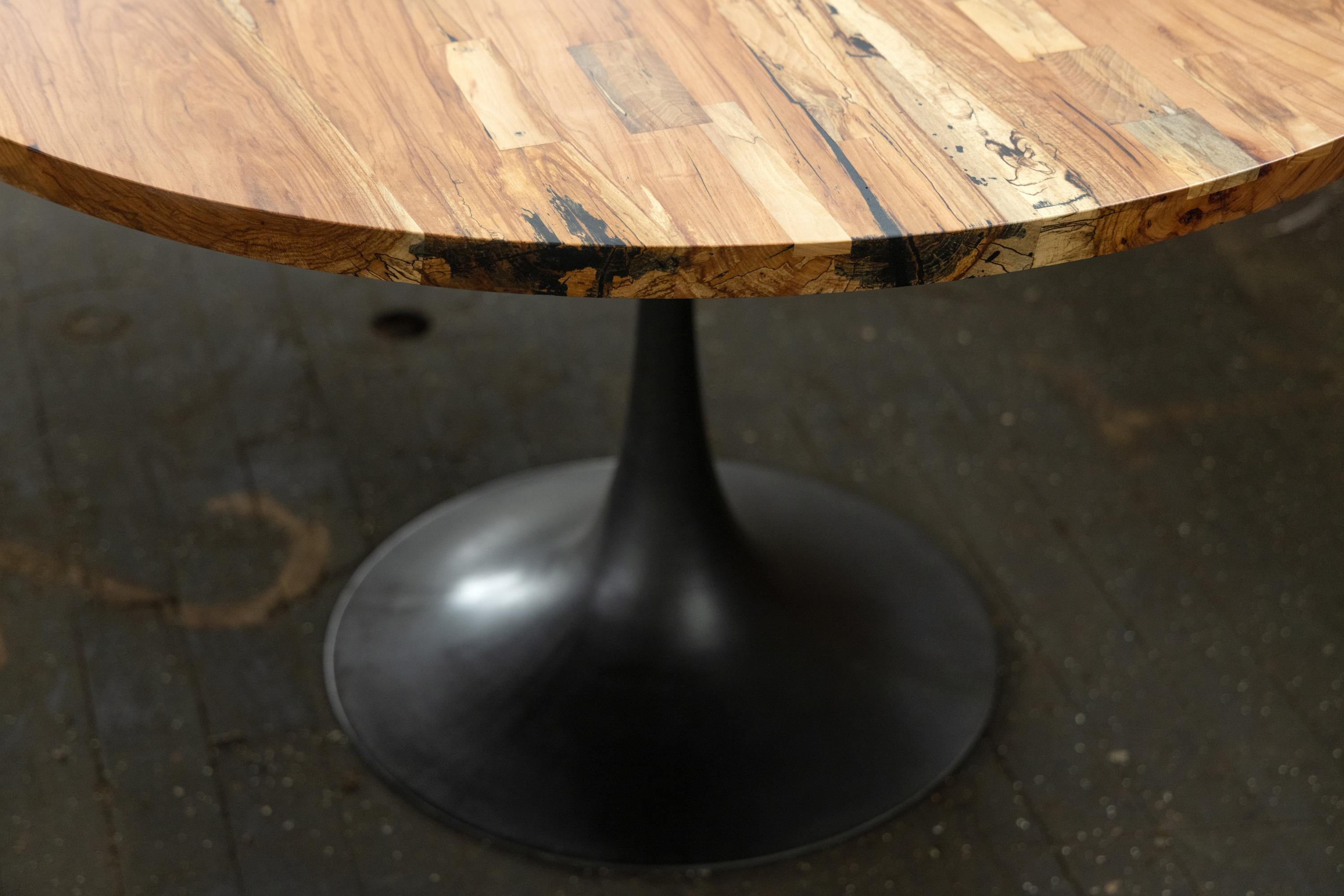 La base de l'Amicalola capte l'espace contre un plateau de table rond ou ovale. Ce socle est moulé à la main par les artisans de la fonderie historique de Sloss Furnaces à Birmingham pour être beau et ne pas gêner les pieds des convives. Riche d'une