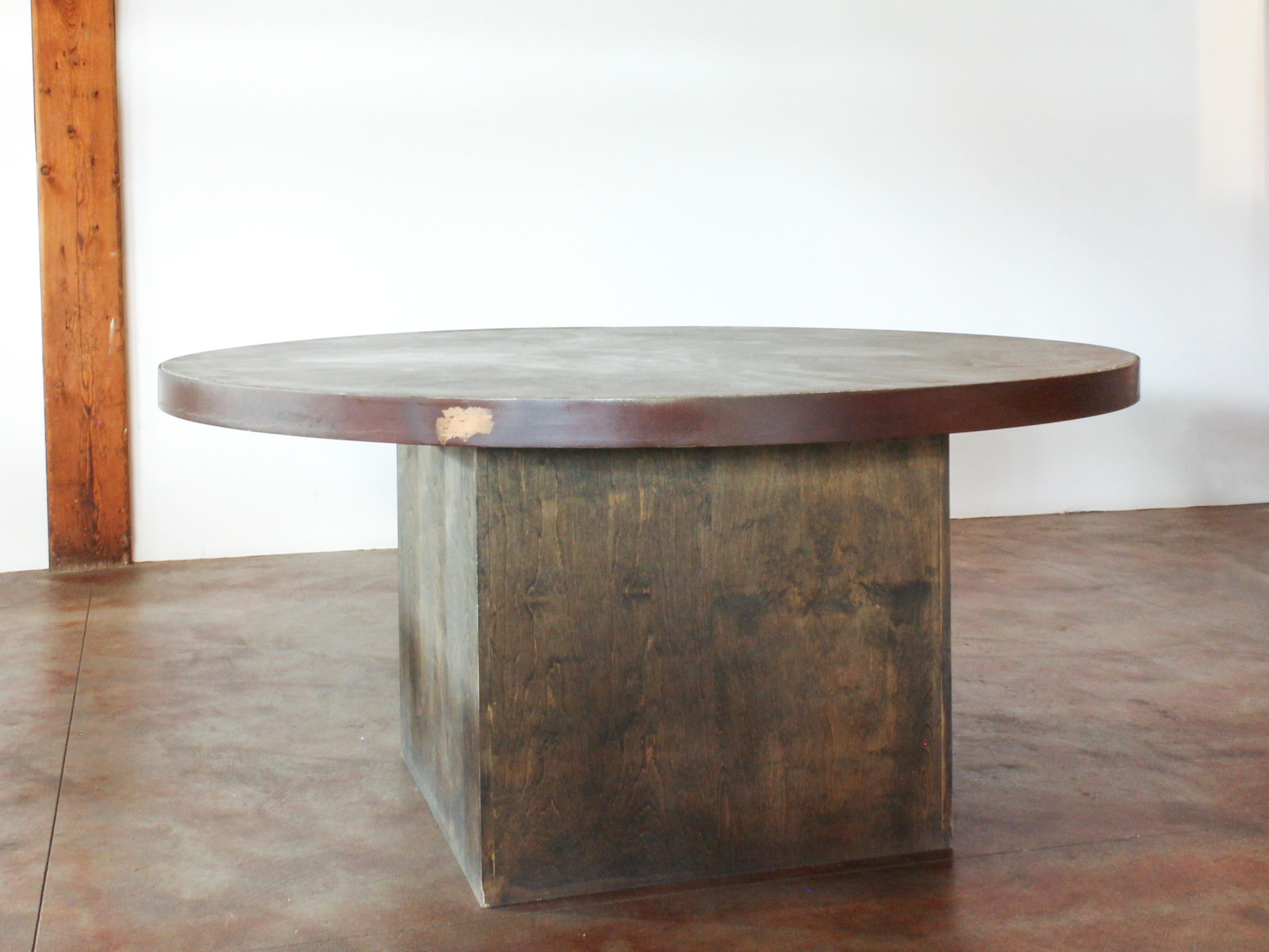 Round pedestal dining table with custom concrete top with steel banding, on a grey aniline dyed wood base. Beautiful patina. Very heavy.
