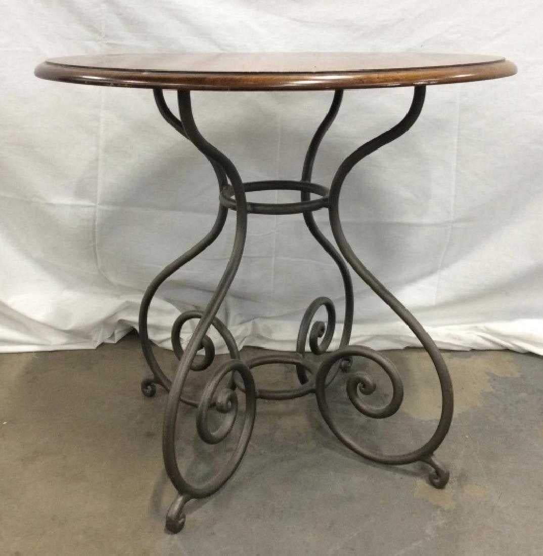 Wooden pedestal table with curled metal base. Round curricular tabletop with dark grey toned metal four legged curved motif base. Pedestal table, end table or side table.