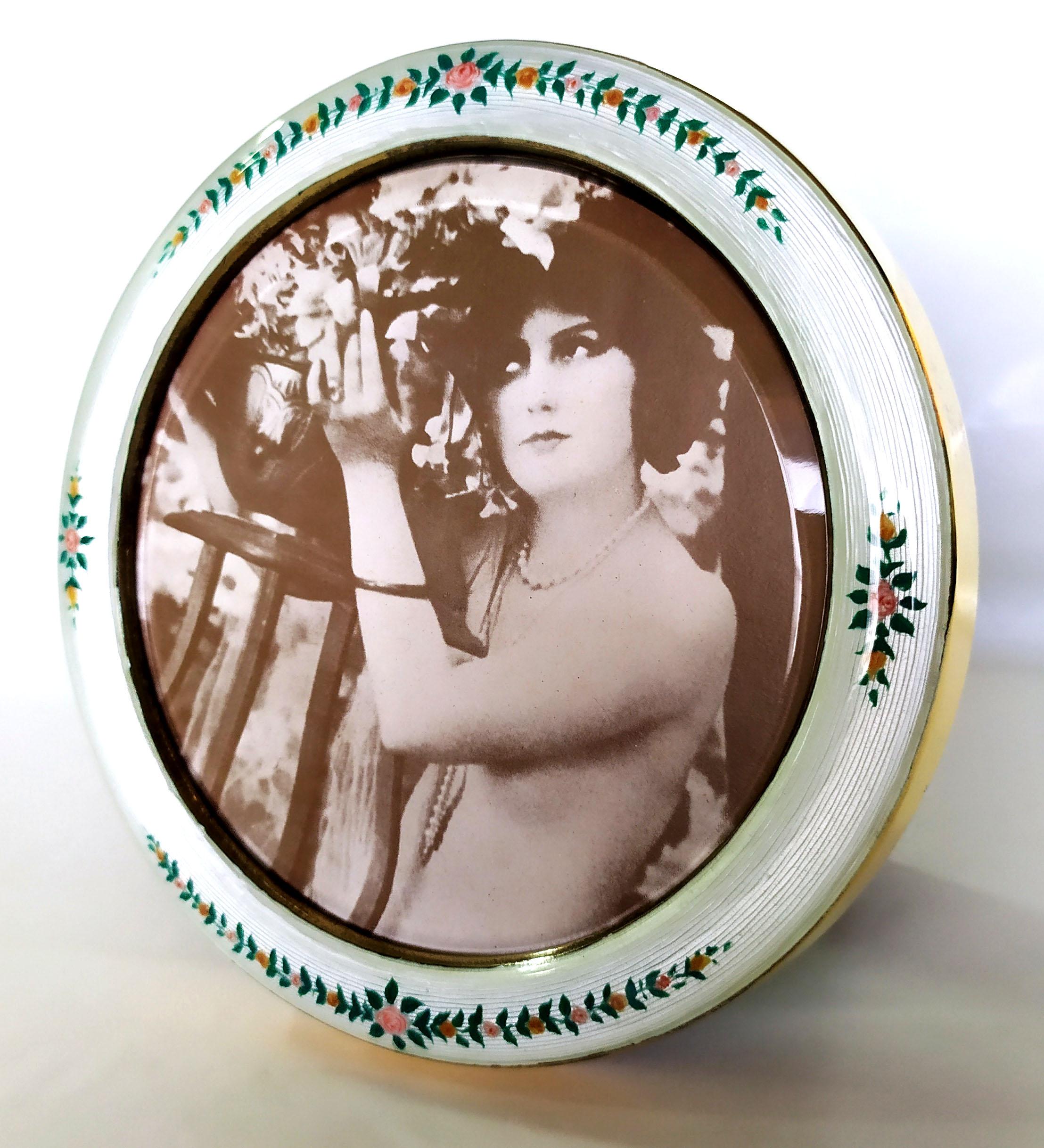 Round photo frame in 925/1000 sterling silver gold plated with translucent fired enamel on guillochè and hand-painted miniature of garlands of flowers in the late 1800s Viennese Art Nouveau style. External diameter cm. 14 internal cm. 11. Weight gr.