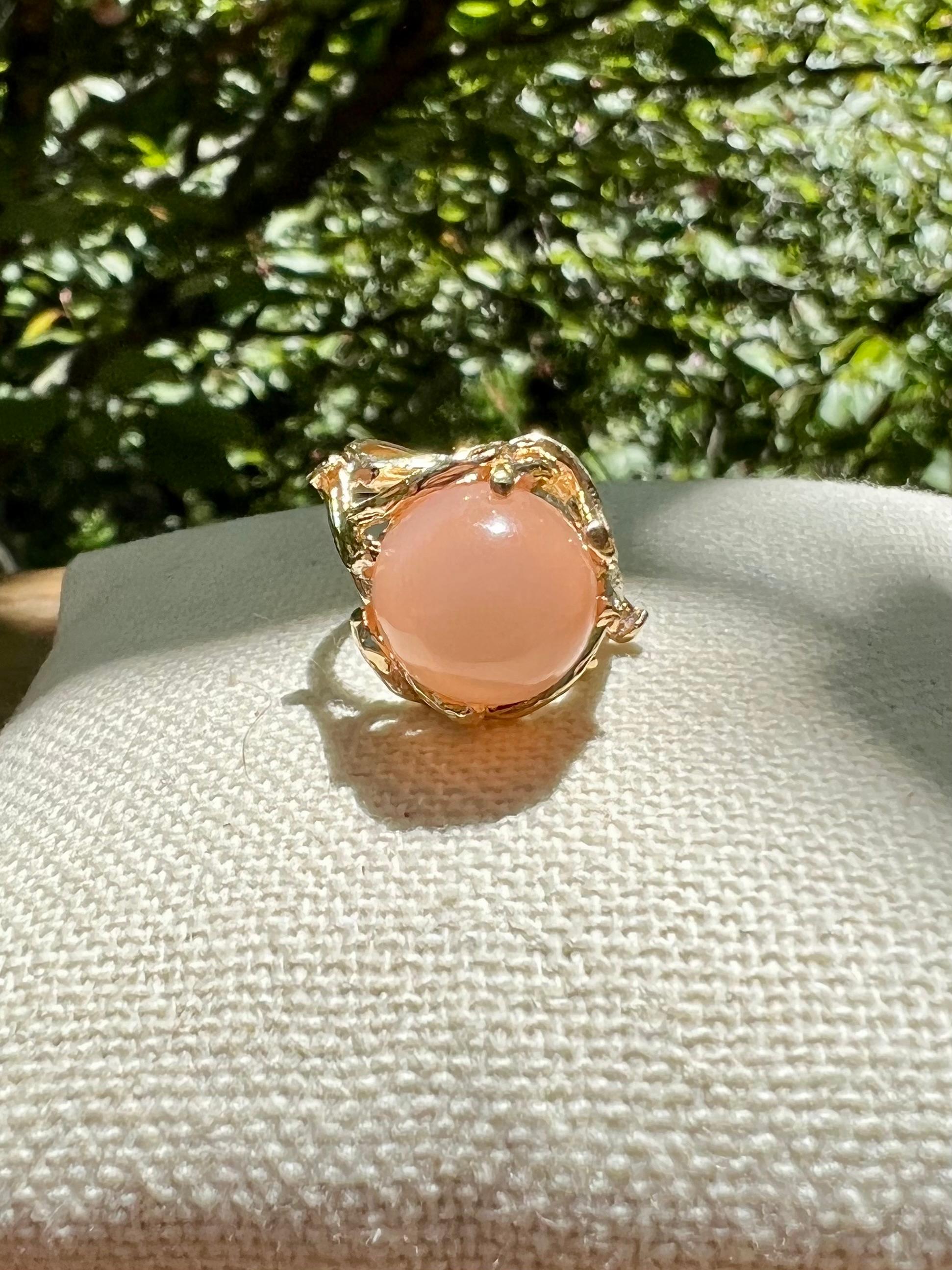 One 14-karat yellow gold ring set with one 11.86 x 11.86 x 8.5mm salmon-colored moonstone set in a branch design setting.  The ring weighs 5.8 grams and is a finger size 5.  The ring can be resized.  Sizing is not included.  