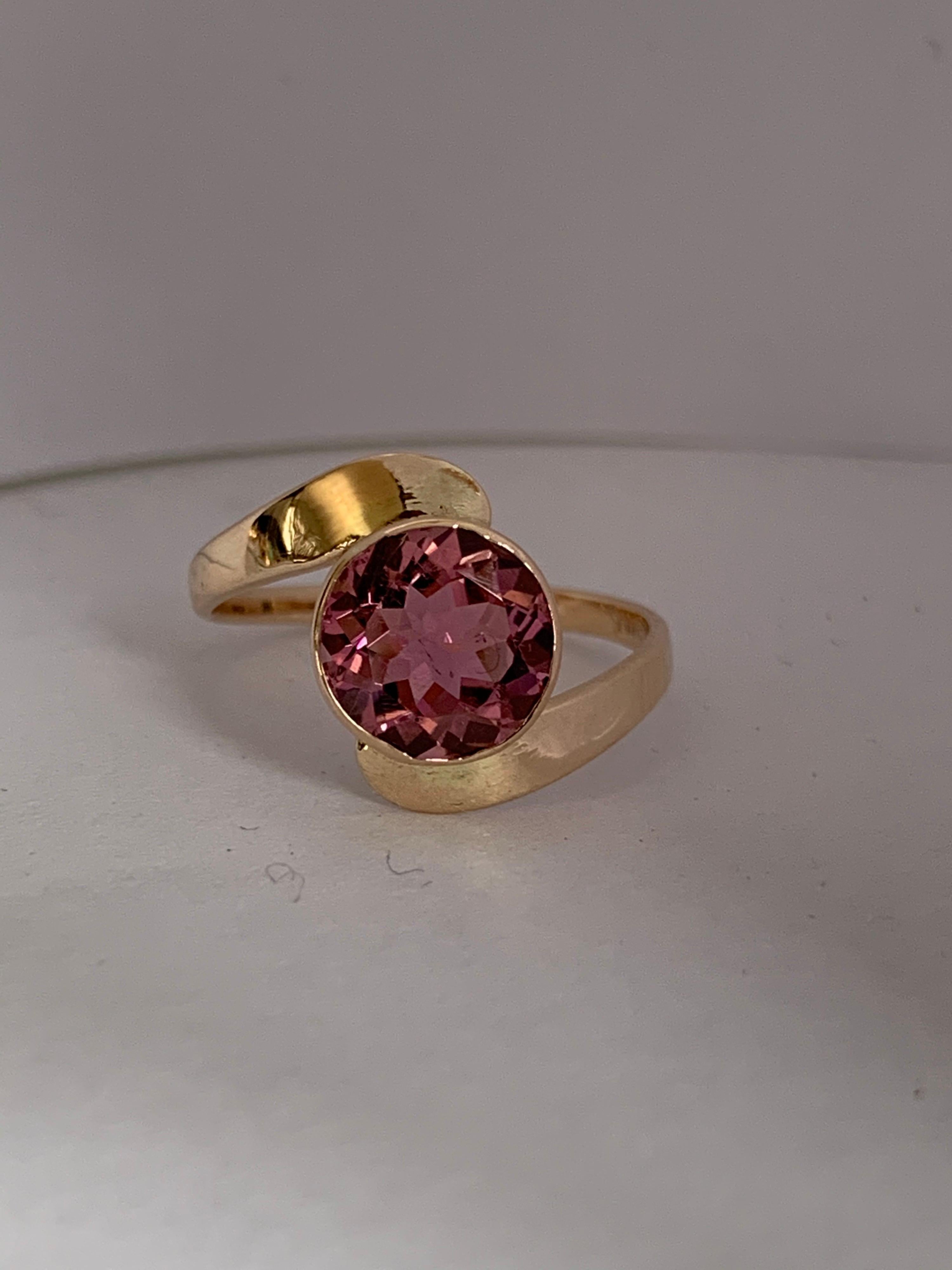Round pink Tourmaline set in 14 Karat yellow gold is handcrafted one of a kind ring. The stone is approximately 1.25 Carat with no inclusion. The ring is size 5 and can be resized if needed.