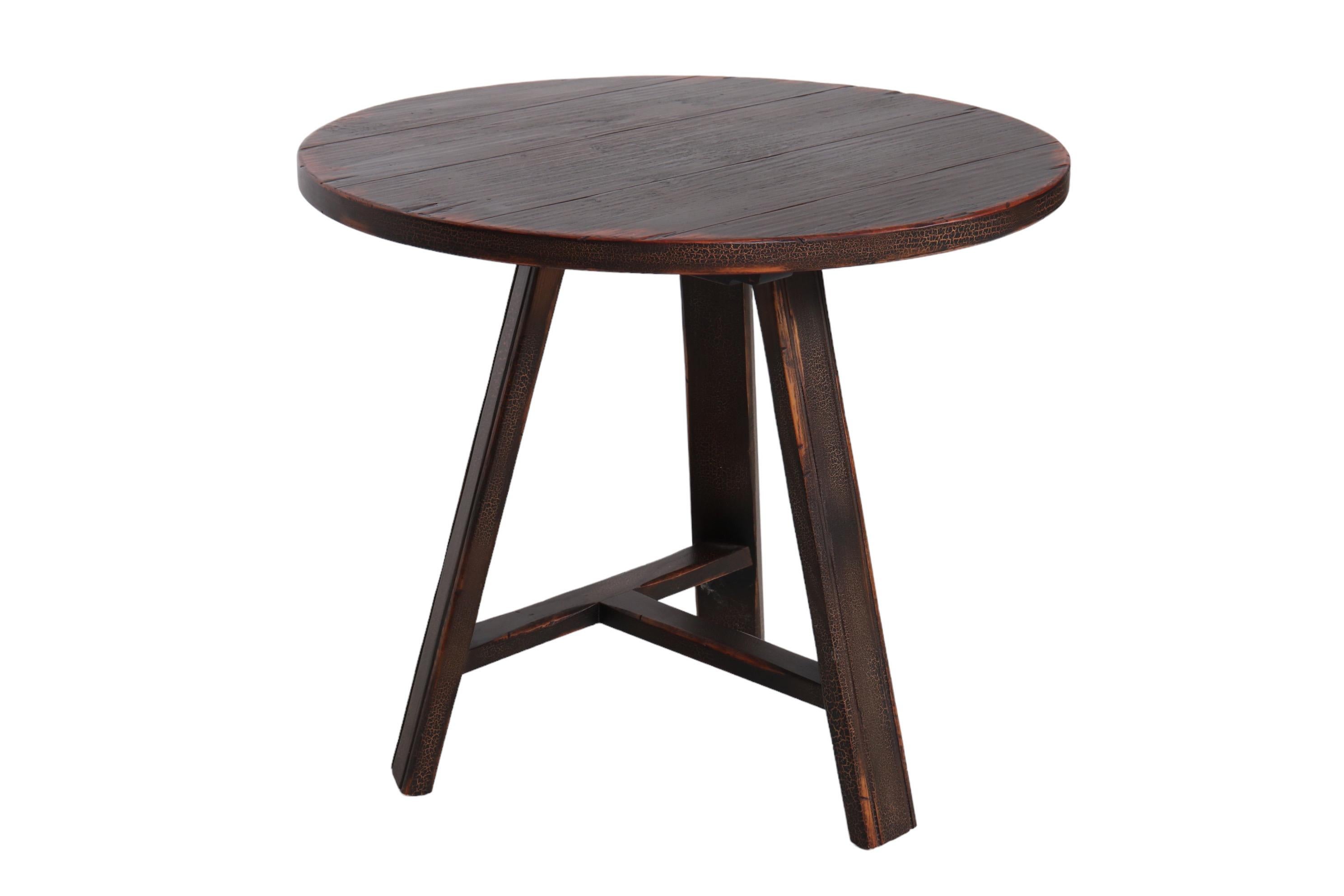 A round wooden accent table made by England Furniture Company of Tennessee. The tabletop is made of planks and stands on three straight legs with beveled edges. Legs are supported with a T-stretcher. Finished throughout with a fired craquelure glaze.