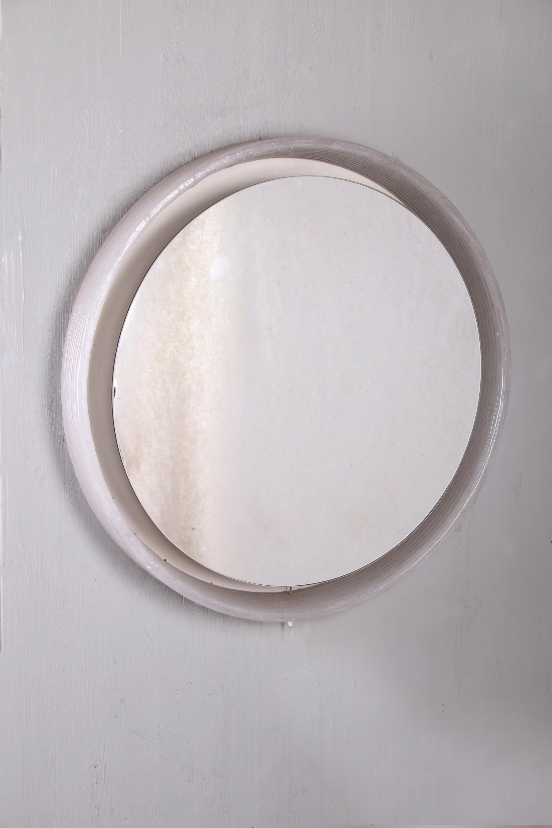 The round mirror from Hillebrand is made of metal with plexiglass and was produced in the 60s.

The mirror has interior lighting which emits a warm soft light when it is on. The mirror is in very good condition. There is a standing edge around the