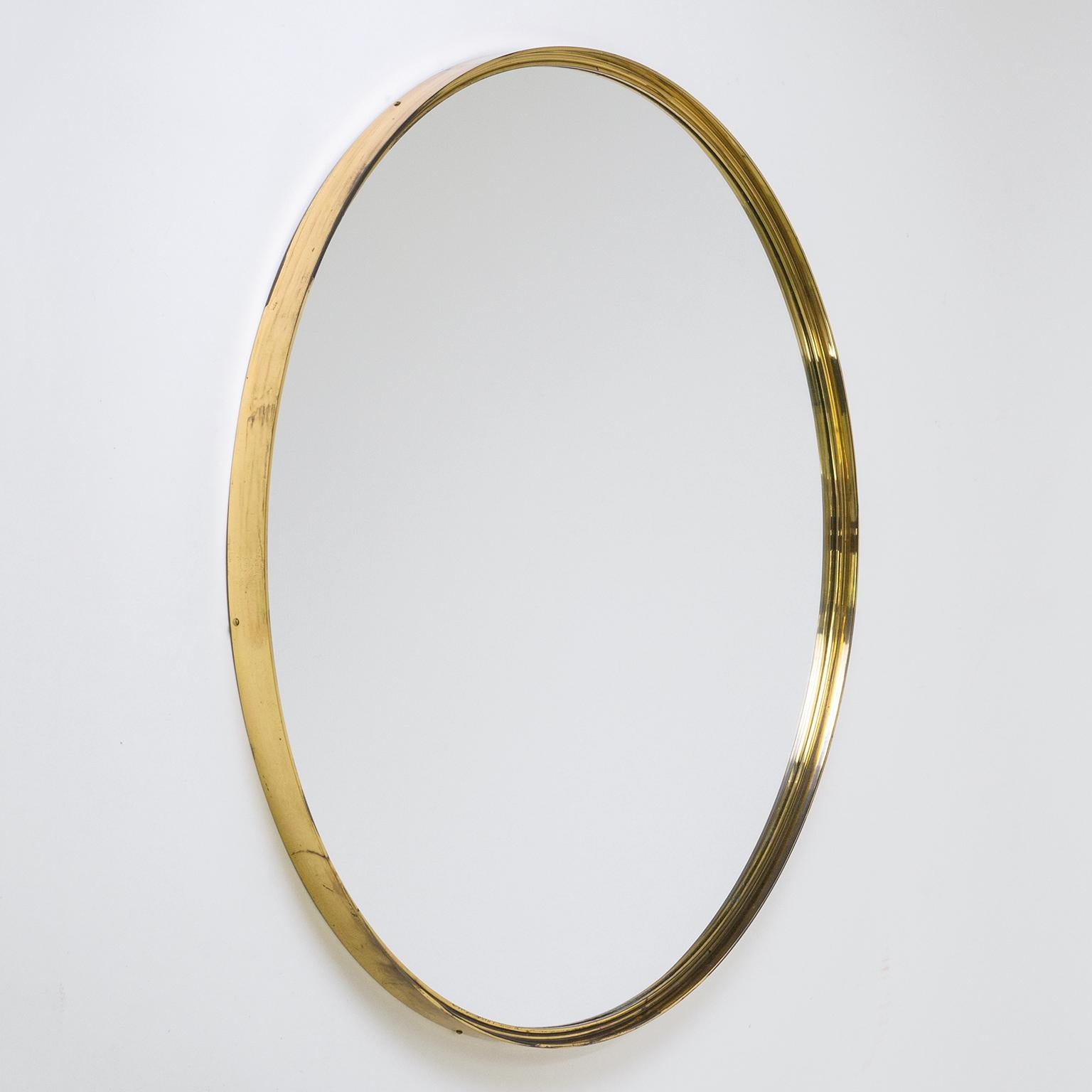 Rare round mirror from the 1950s with a continuous and profiled brass frame. Very solid build with thick brass and original mirror. Nice vintage condition with patina on the brass and light streaks to the silver coating of the original mirror.