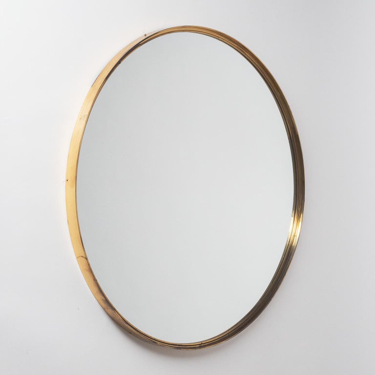 Rare round mirror from the 1950s with a continuous and profiled brass frame. Very solid build with thick brass and original mirror. Nice vintage condition with patina on the brass and light streaks to the reflective coating of the original mirror.