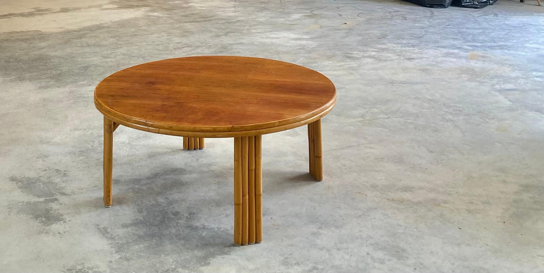 Una elegante y escultural mesa de centro de ratán de poste redondo con una superficie de chapa de nogal bellamente limpia que aporta calidez y sofisticación. La base cilíndrica de la mesa se compone de palos de ratán tensamente dispuestos, que