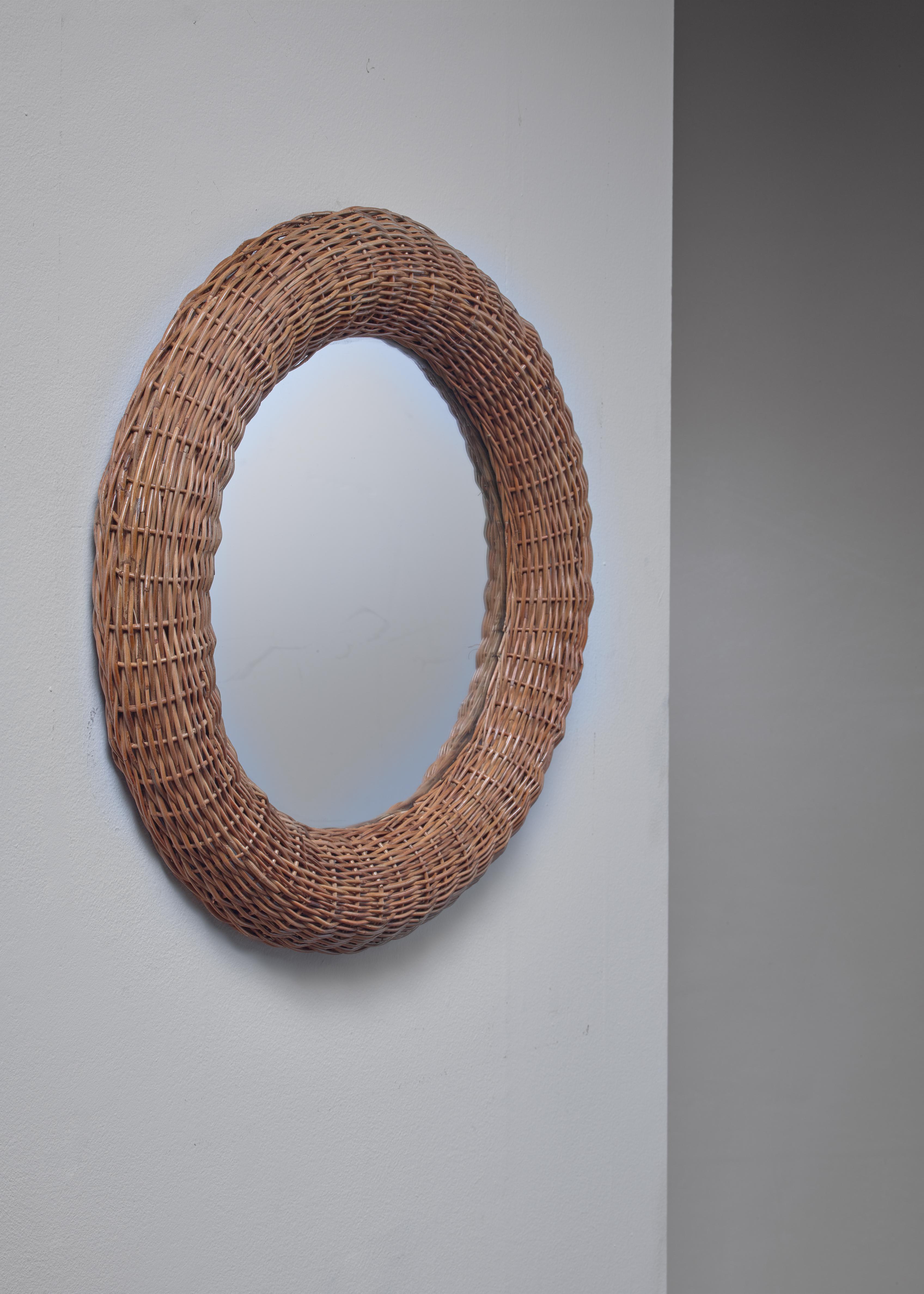 A large round mirror in a woven rattan frame.