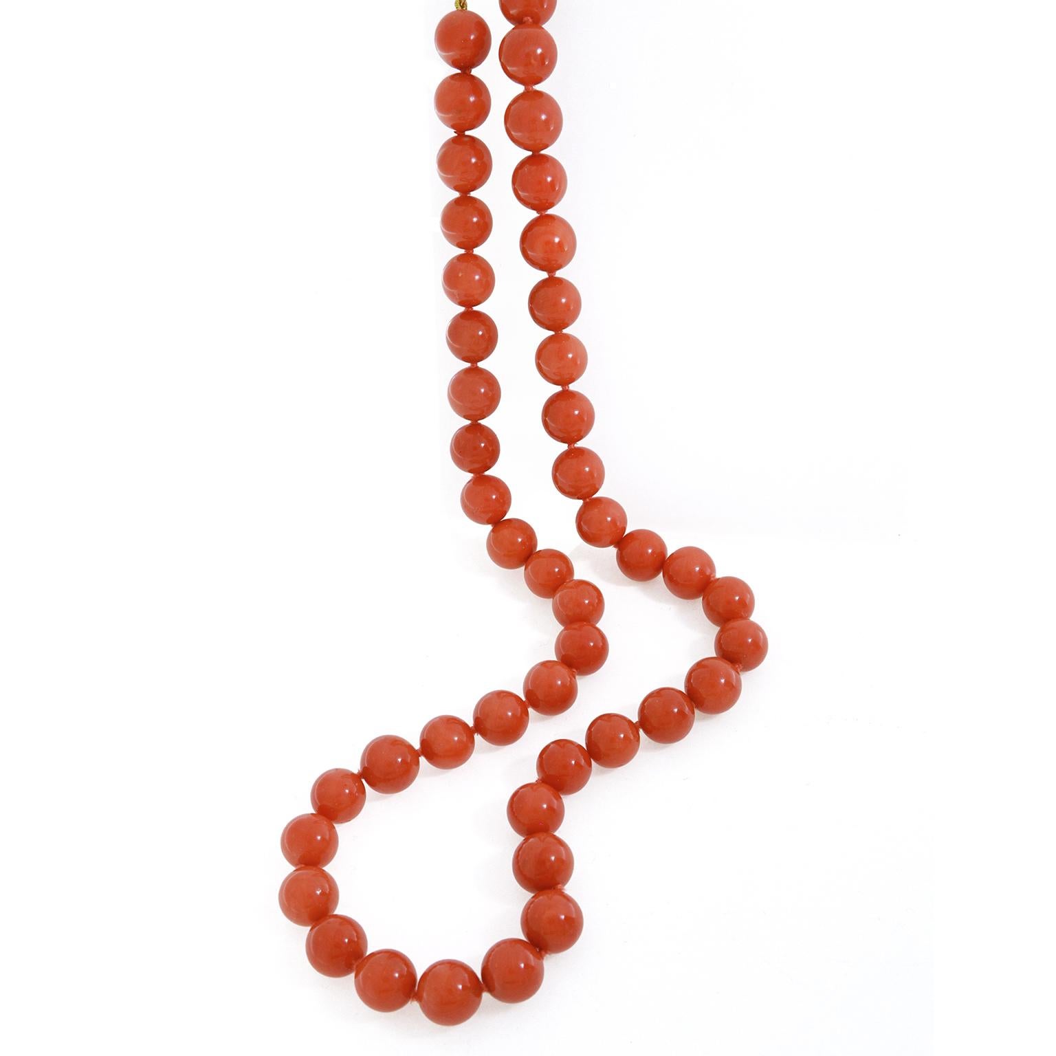 Fiery orange red coral is the essence of this beaded necklace. Orbs of the gem are strung on a thread of a coordinating shade in a graduated arrangement. At the ends of the necklace, the coral is 11.4 mm. This widens to 12mm in the center. The total