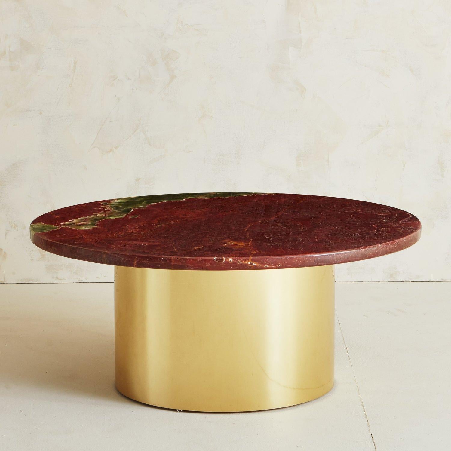 A beautiful coffee table featuring a 1.25” thick red onyx tabletop with stunning green and gray veining. This table has a custom built round cylindrical base wrapped in polished brass. This piece is truly one of a kind and would elevate any