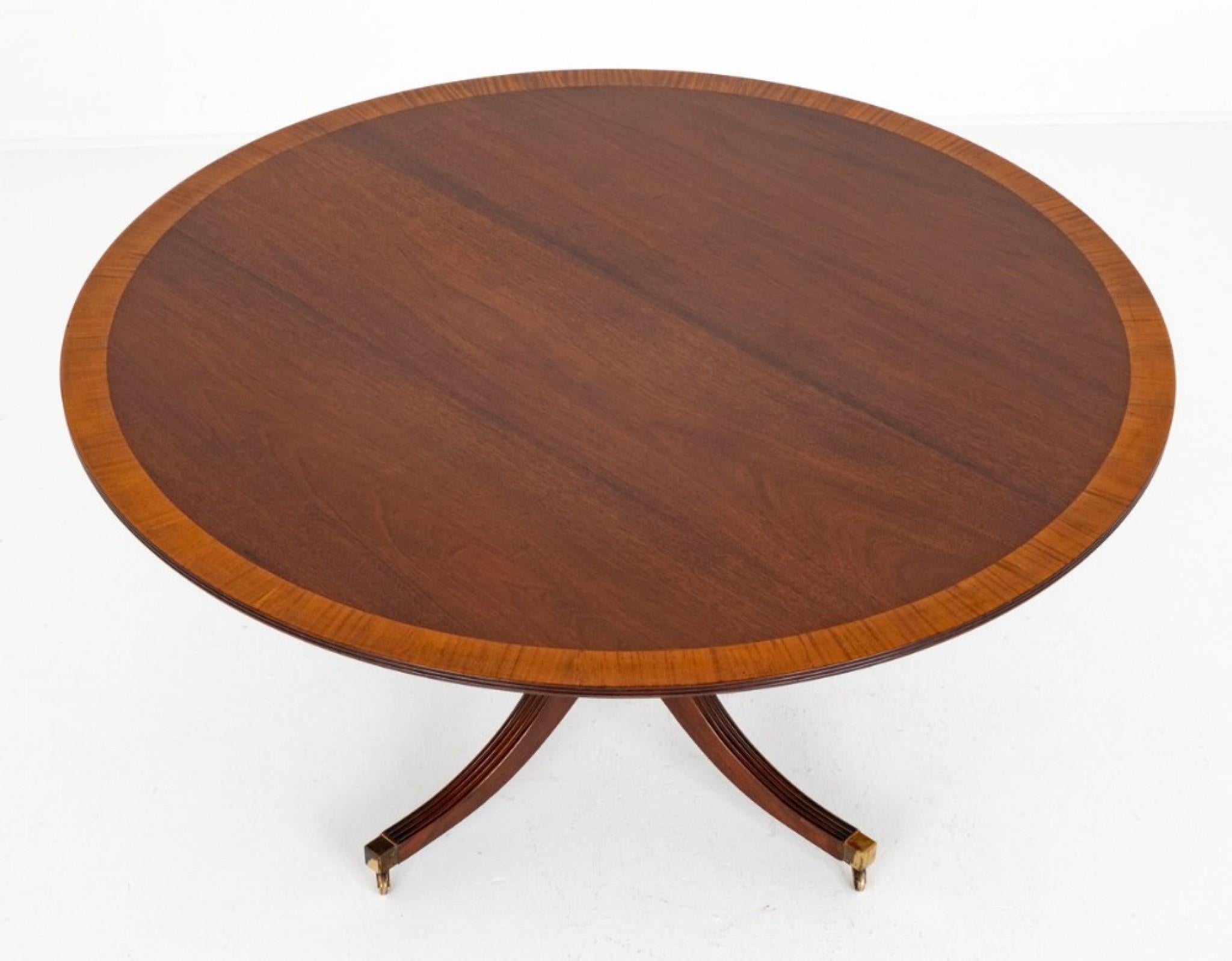 Regency Revival Mahogany Circular Dining Table.
Circa 1920
This Table is Raised Upon an Elegant Base with Swept Legs Terminating in Brass Box Castors.
The Column Being of a Gun Barrel Form.
The Top of the Table Having Satinwood Cross-banding and