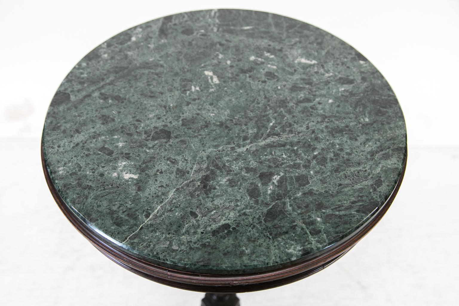 This round Regency marble top occasional table is made of rosewood and has a removable green marble top with a chamfered outer edge. The apron is fluted, and the stem, also fluted, has a knop carved with acanthus leaves and a ring of repeating
