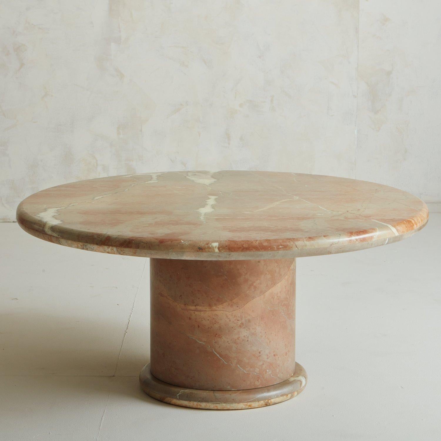 A polished Rojo Alicante marble coffee table featuring a round 2” thick tabletop on a circular base with a banded-edge detail. The tabletop has a wood stone tap on the underside, allowing it to sit securely in the base. This marble is a stunning