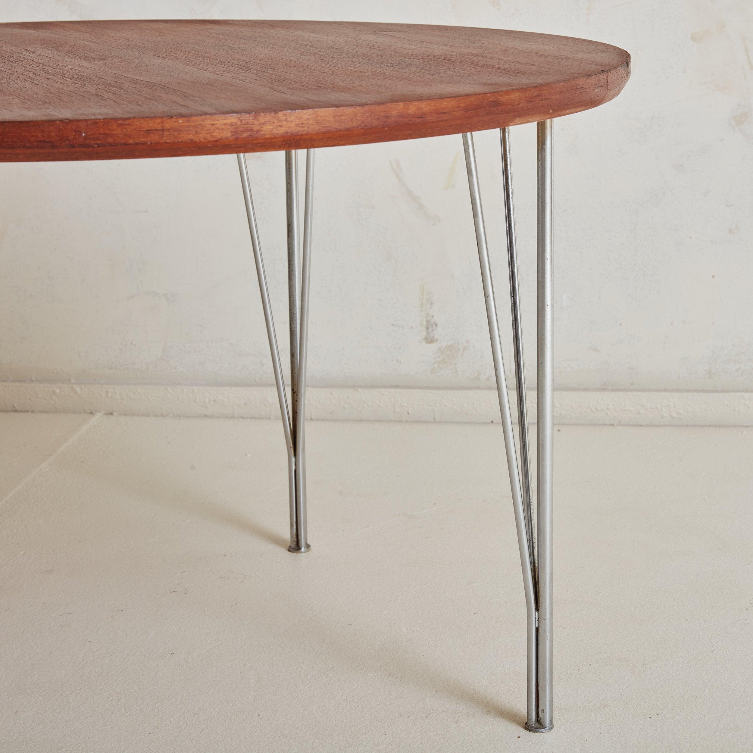 A Danish Modern round coffee table featuring a gorgeous cherry hued rosewood top with natural graining throughout in a slightly deeper shade. Four minimalistic hairpin legs constructed of chrome support the top and add an industrial element to the