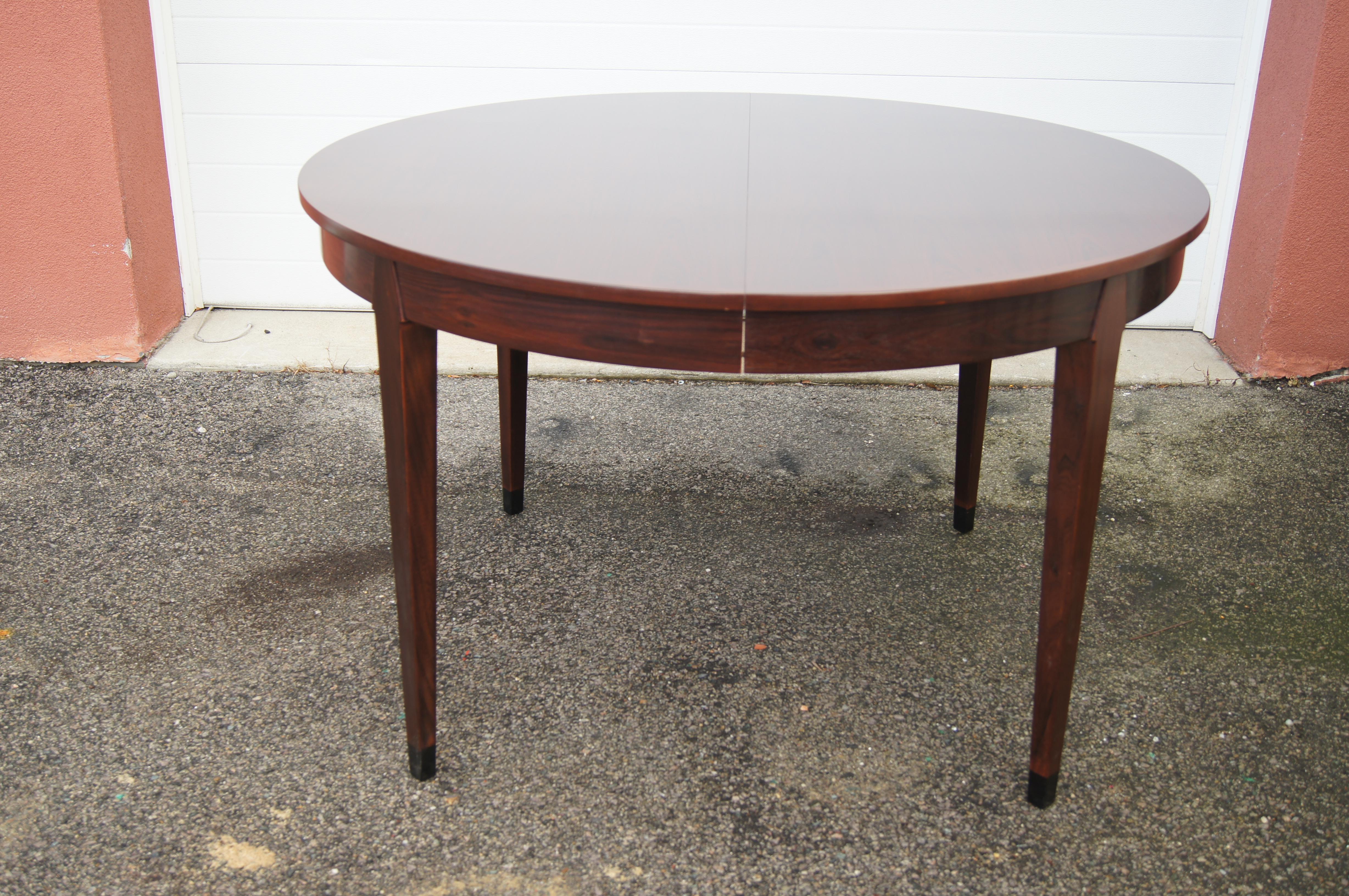 Der dänische Modernist Arne Vodder entwarf diesen runden Esstisch aus Palisanderholz mit konischen Beinen in den 1960er Jahren. Mit einer zusätzlichen Platte (19,75 x 49,18 Zoll) wird er zu einem breiteren ovalen Tisch von 68,75 Zoll erweitert.