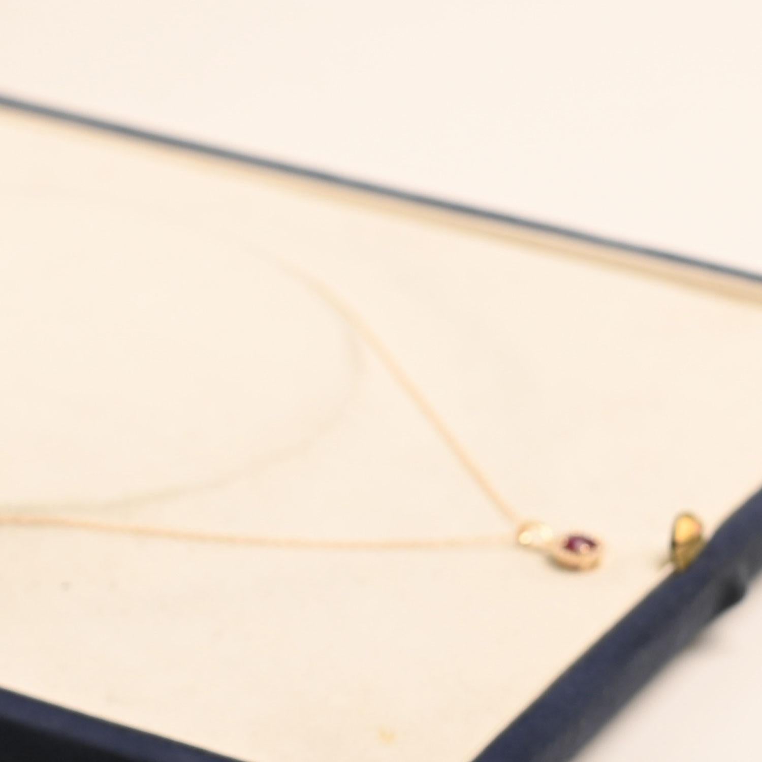 A beautiful pendant necklace featuring a vibrant 0.50-carat round ruby set securely in prongs. Surrounding the center stone is a delicate halo of diamonds weighing approximately 0.07 carats, adding a soft sparkle that enhances the ruby’s brilliance.