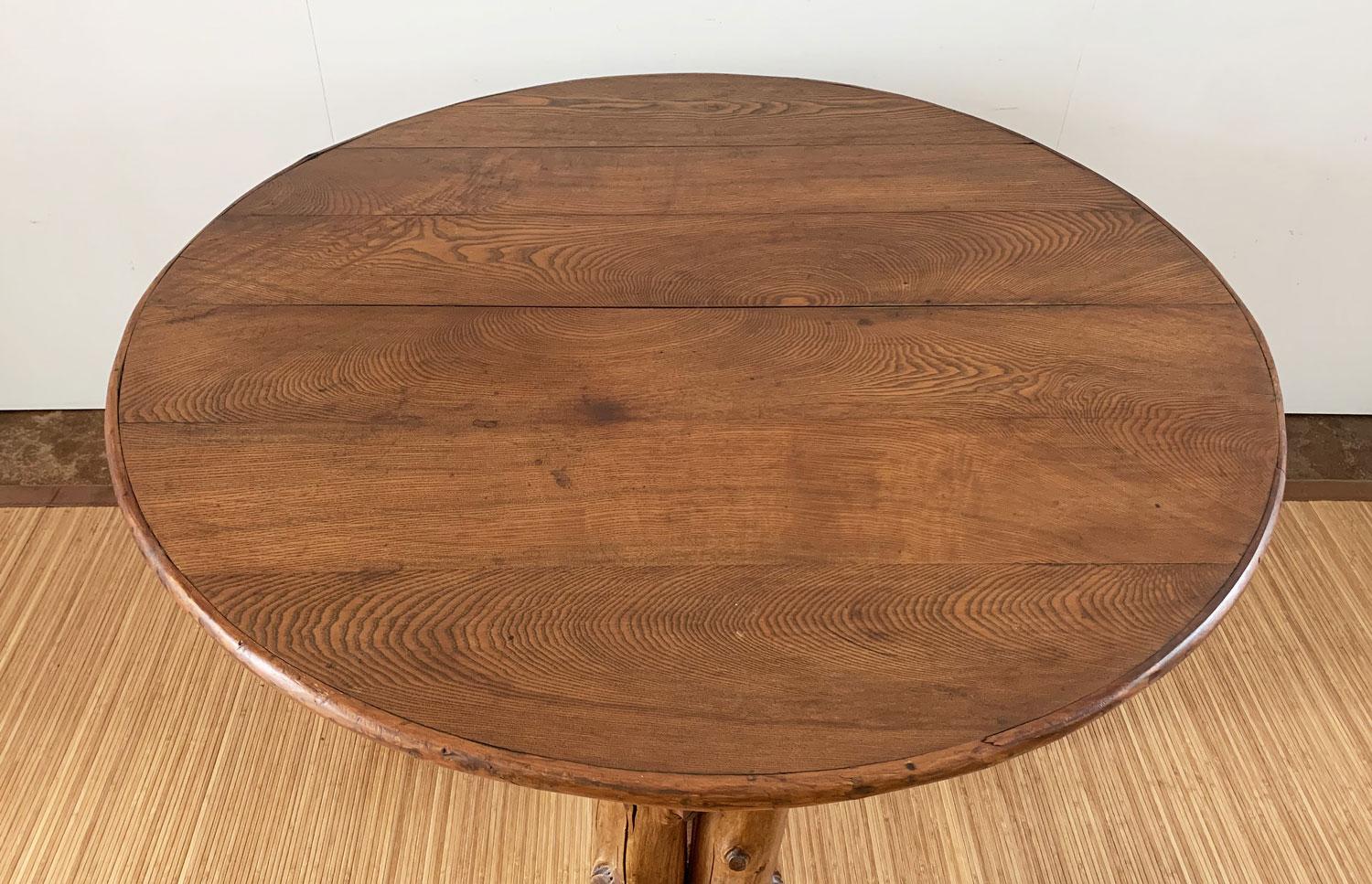 This one-of-a-kind round table has a quintessential rustic design with a cedar peeled pole base and an ash board top wrapped with peeled cedar edging. Beneath the top, the apron is embellished with applied cedar half-rounds. The double cedar pole