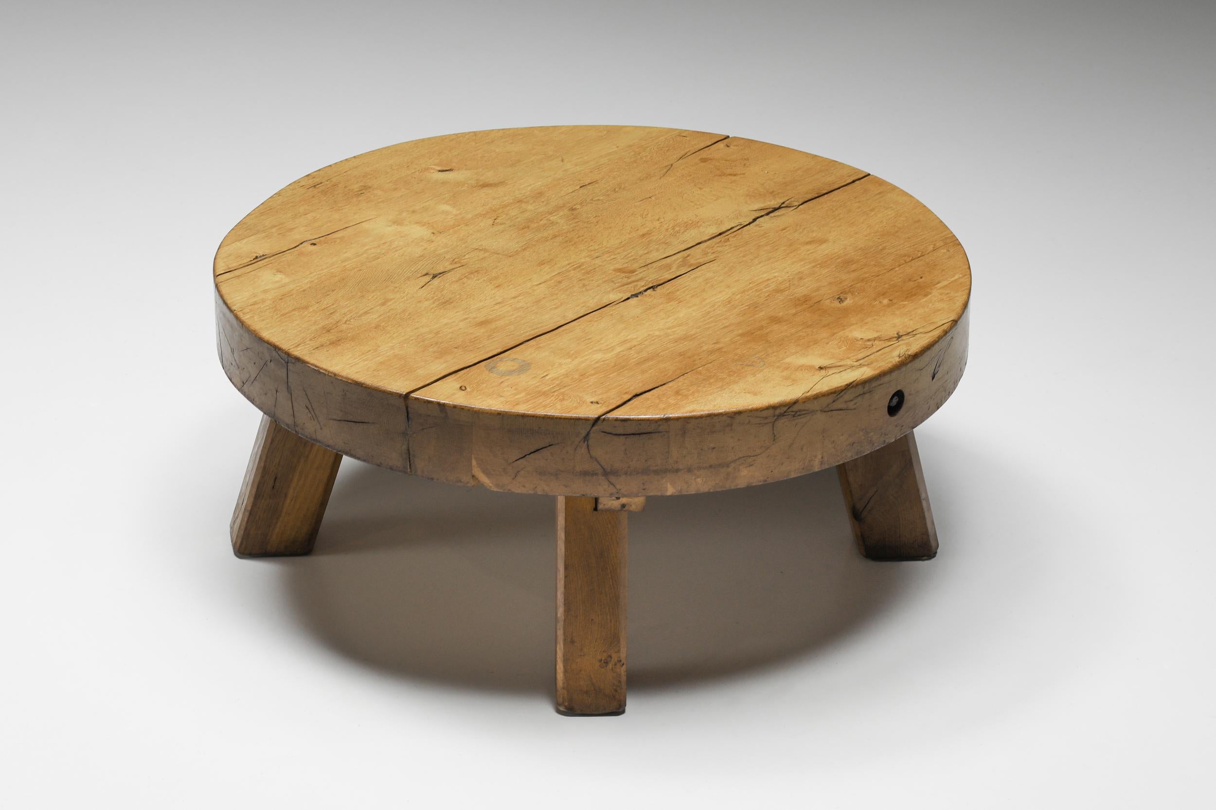 Round rustic wooden coffee table, France, 1950's.

This rustic round coffee table with a four-legged base is made of solid wood. The rounded surface provides space for objects like magazines and other curiosities. Can also be used as a side table.