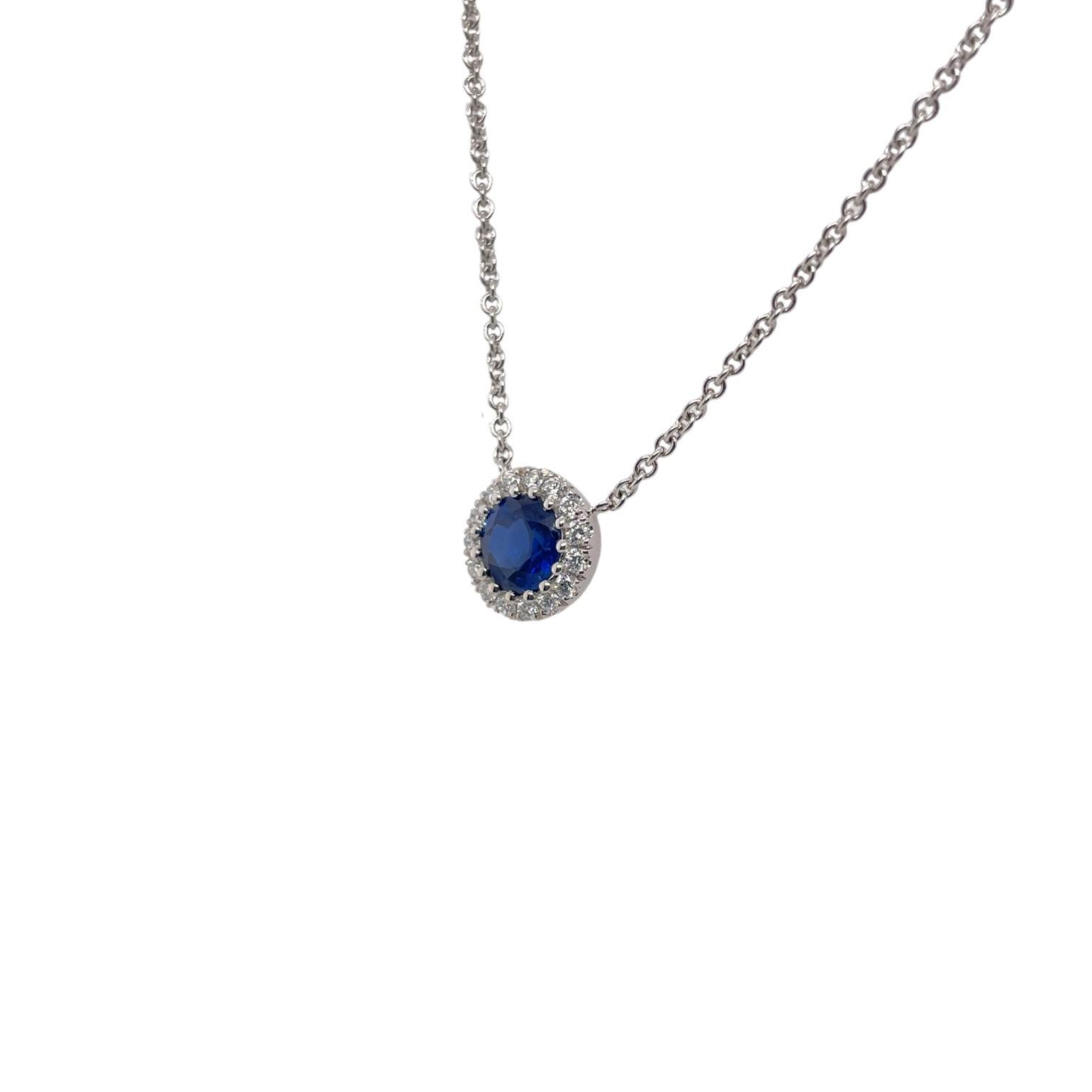 Sapphire & Diamond cluster pendant in 14k white gold contains 1 center round brilliant sapphire, 0.95ct and 15 round brilliant diamonds surrounding, 0.18tcw.  Diamonds within halo are near colorless and VS in clarity, excellent cut. All stones are