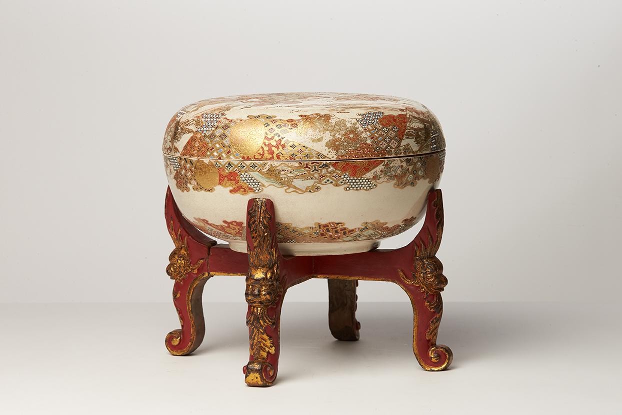 Round Satsuma ware box painted in polychrome enamels and gold. The top of the lid is decorated with Japanese characters in a landscape. The interior of the lid is decorated with another landscapes, birds and trees, in Japanese prints style. The