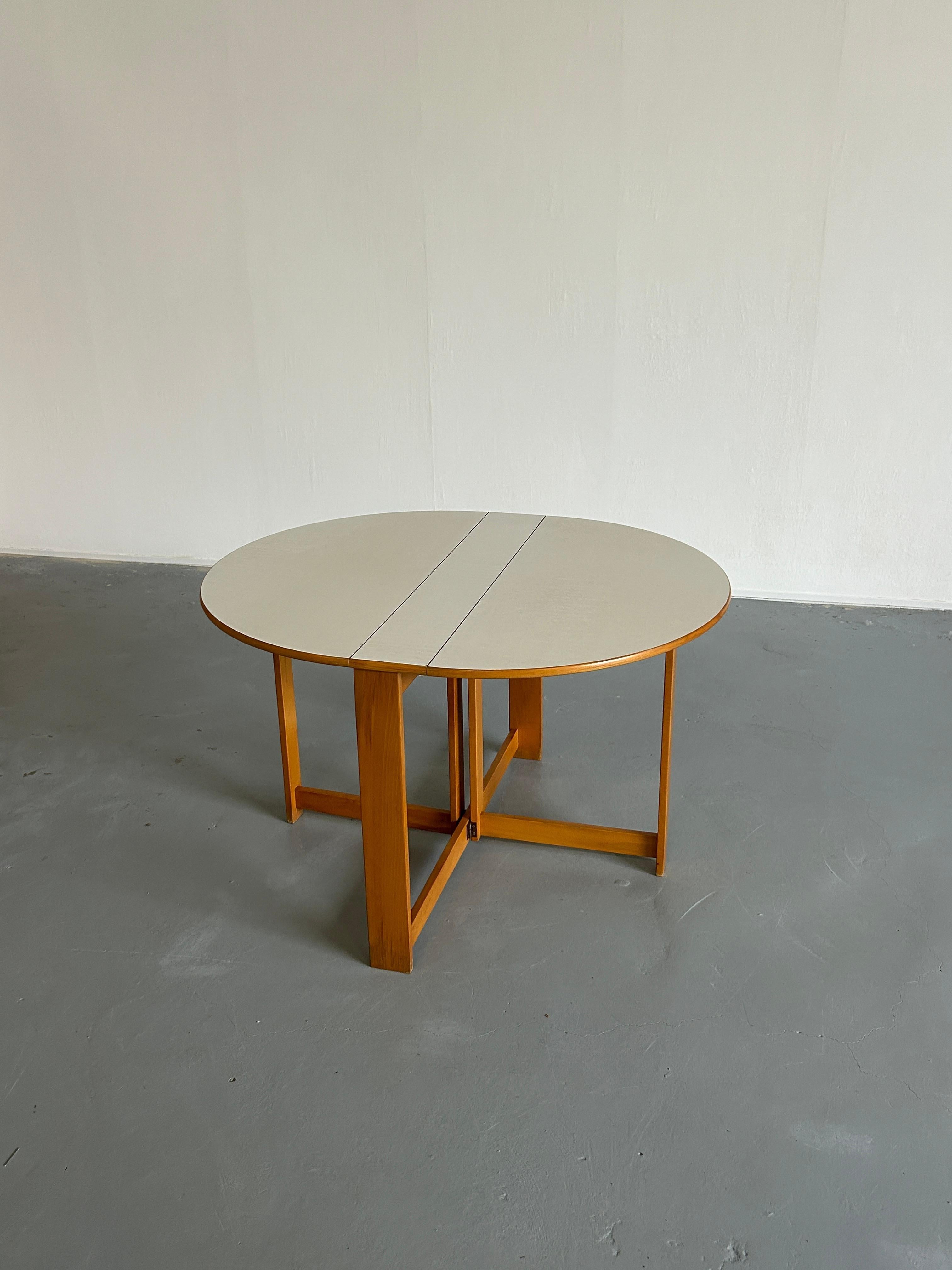 Scandinavian Mid-Century-Modern foldable dining table with side wings. The oval top is made of white formica, typical of the period. The frame is made of oak wood. A modern and functional piece of furniture, perfect for a small room. Can easily seat