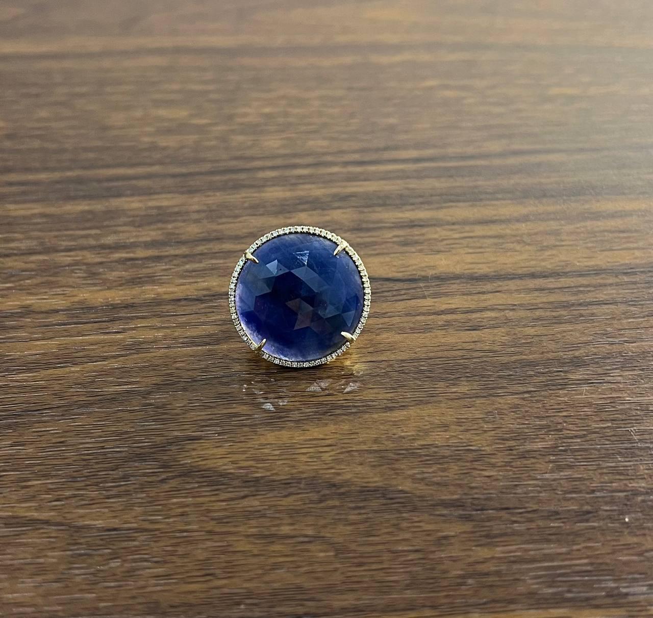 Elegant Blue Sapphire & Diamond Ring. This exquisite piece features a large, round blue sapphire set in a halo of sparkling diamonds. The sapphire is faceted, enhancing its deep blue hue. The ring is crafted with precision, showcasing the gemstone's
