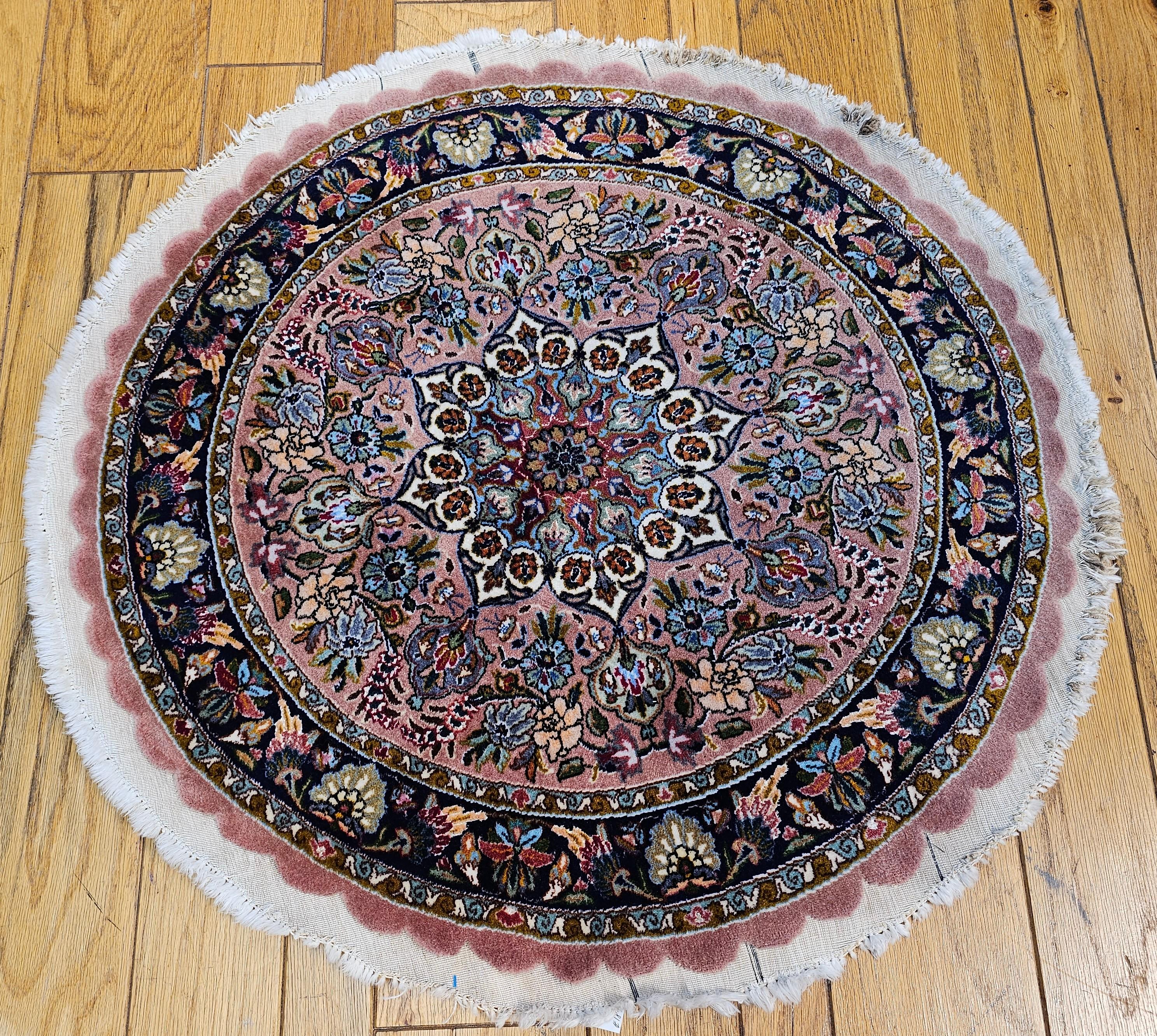 A rare and exquisite find, this round-shaped vintage Persian Tabriz rug from the fourth quarter of the 20th century showcases masterful weaving and timeless elegance. The soft pale pink field is adorned with an intricate array of floral and branch