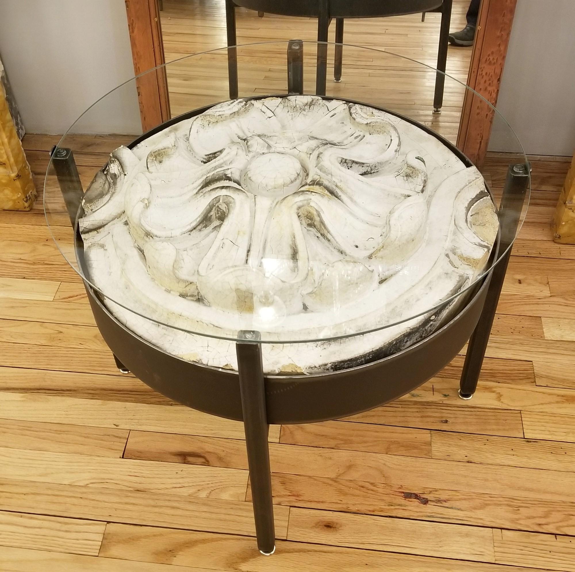 Recovered from a NYC building, this architectural glazed terra cotta flower piece has been made into a round side table. The iron table base is finished with a quarter inch thick glass on top. Please note, this item is located in one of our NYC