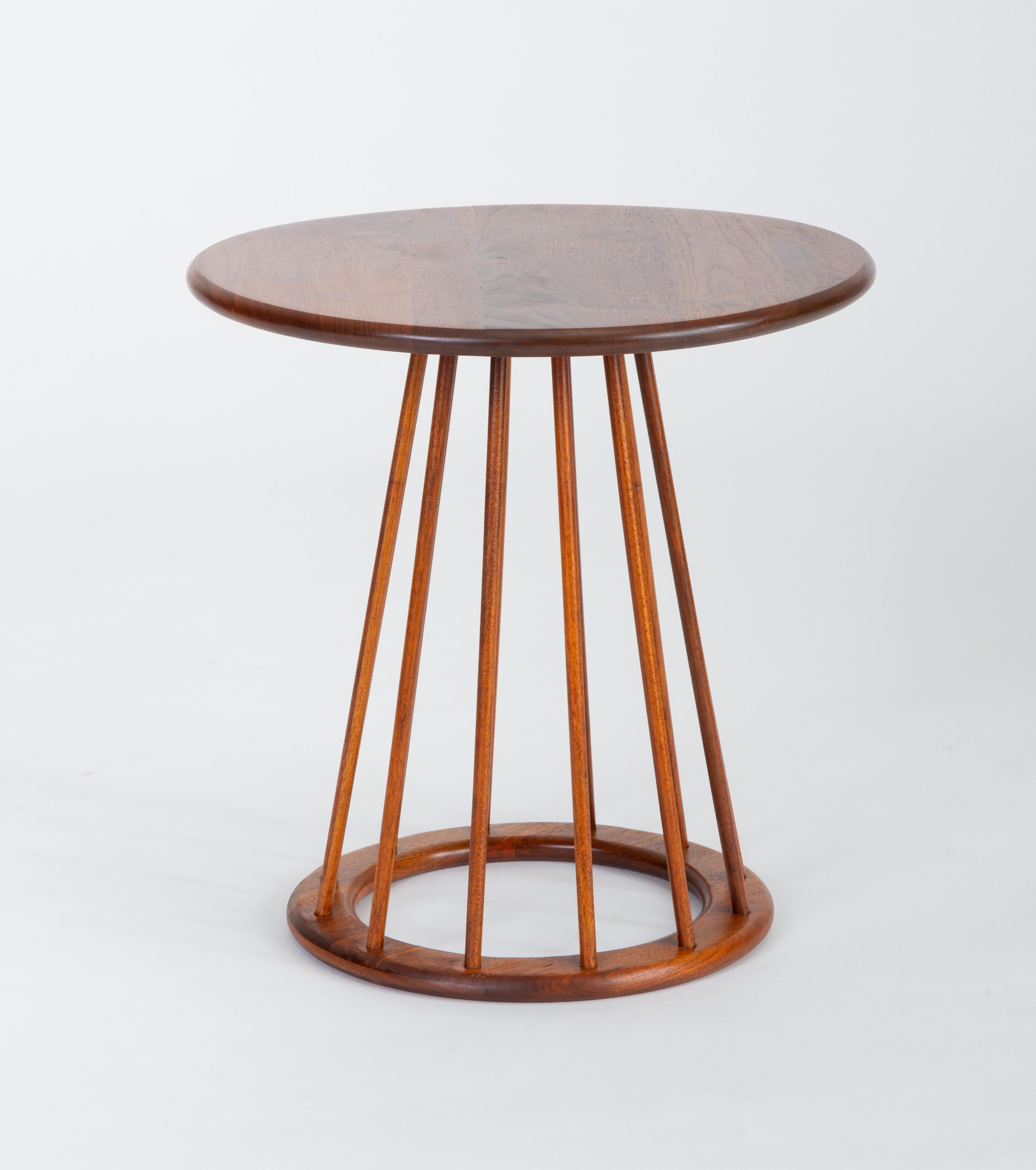A simply constructed side table from the late 1950s by Arthur Umanoff for New Jersey-based Washington Woodcraft. The table has a round, bull-nosed surface of solid walnut supported by a pedestal base; a smaller ring in matching walnut wood with