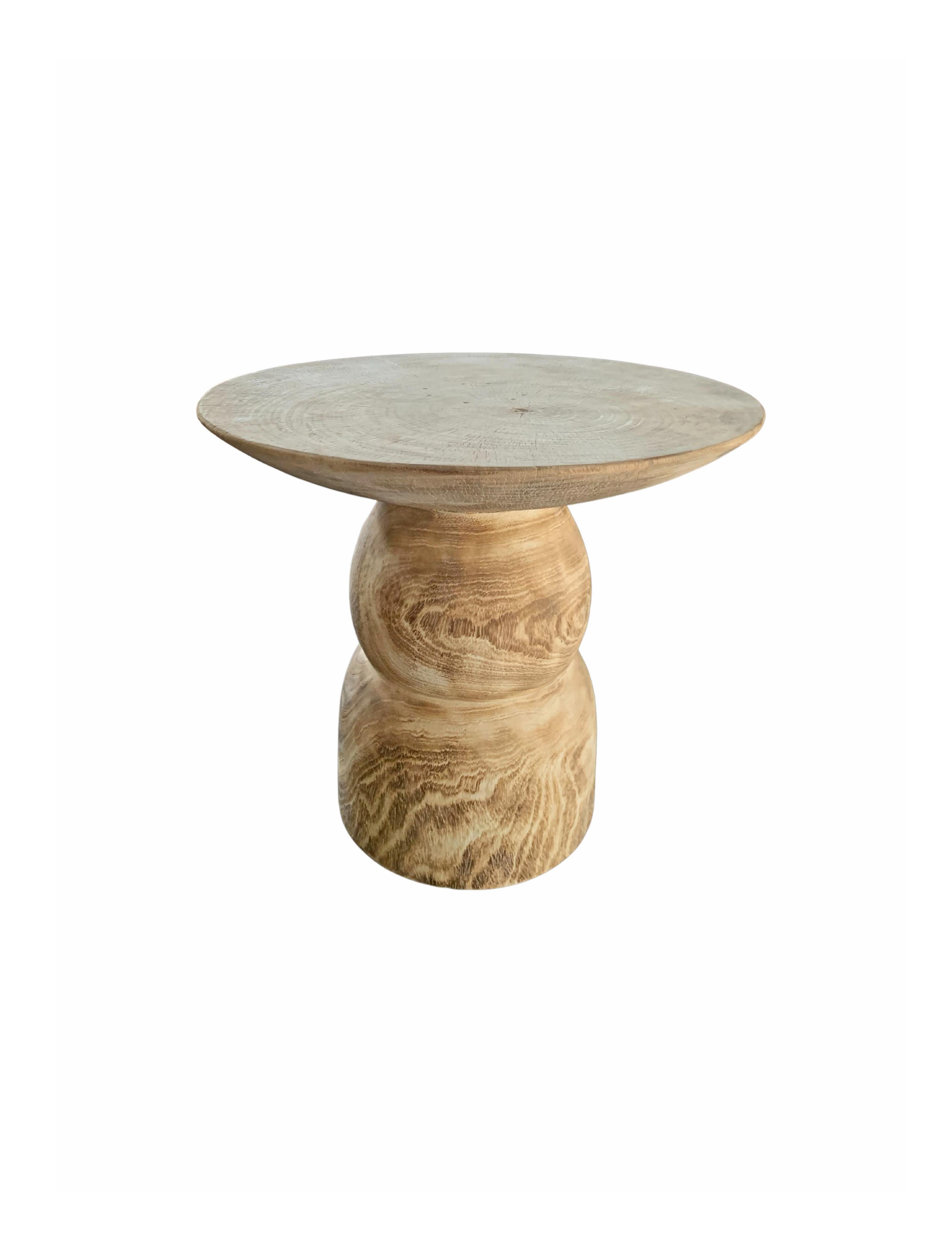 A wonderfully organic round side table. Its pigment was achieved through a bleaching process. Its neutral pigment and subtle wood texture makes it perfect for any space. A uniquely sculptural and versatile piece, this table was crafted from mango