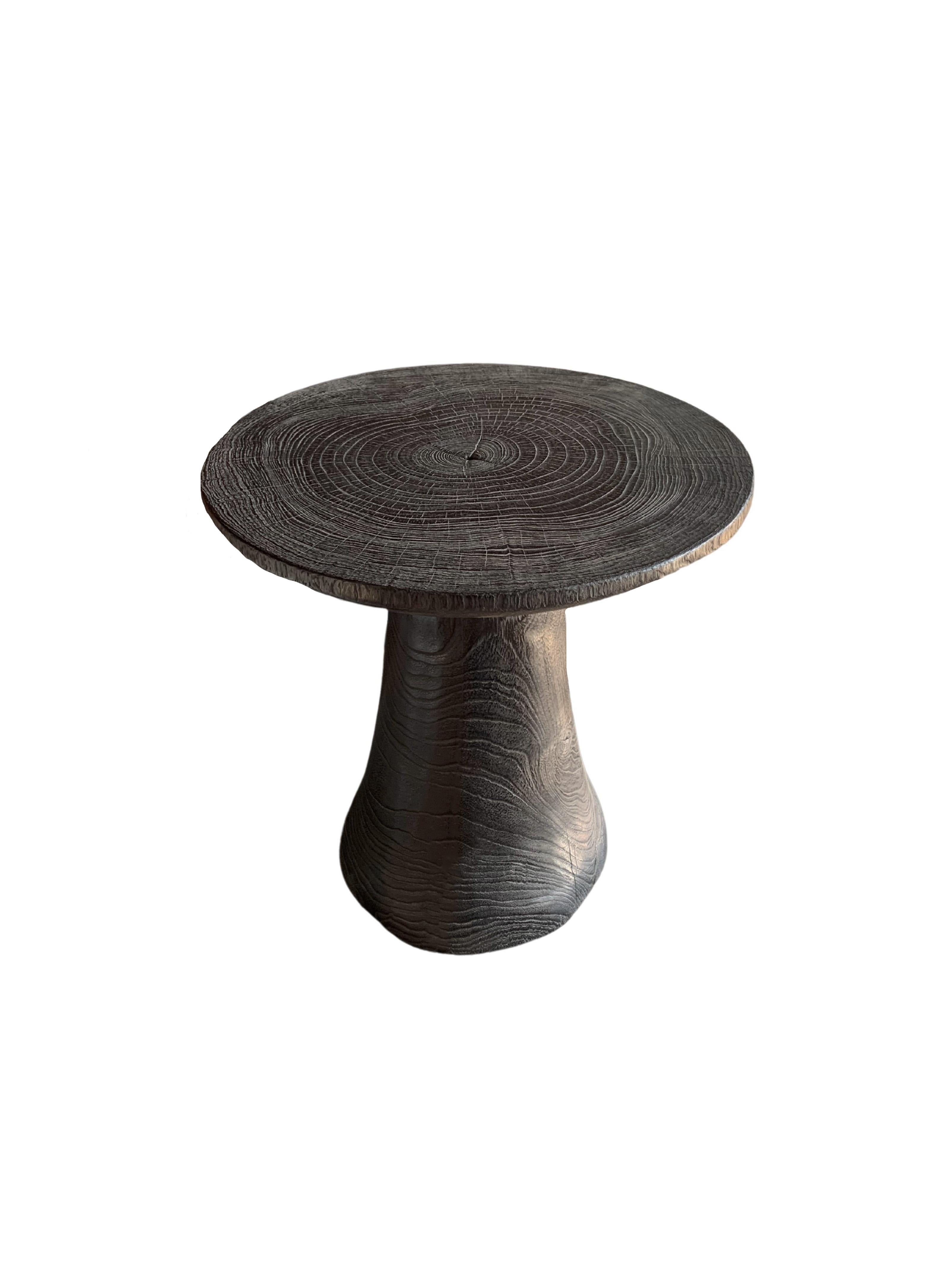 A wonderfully organic round side table. Its rich black pigment was achieved through burning the wood three times. Its neutral pigment and subtle wood texture makes it perfect for any space. A uniquely sculptural and versatile piece certain to invoke