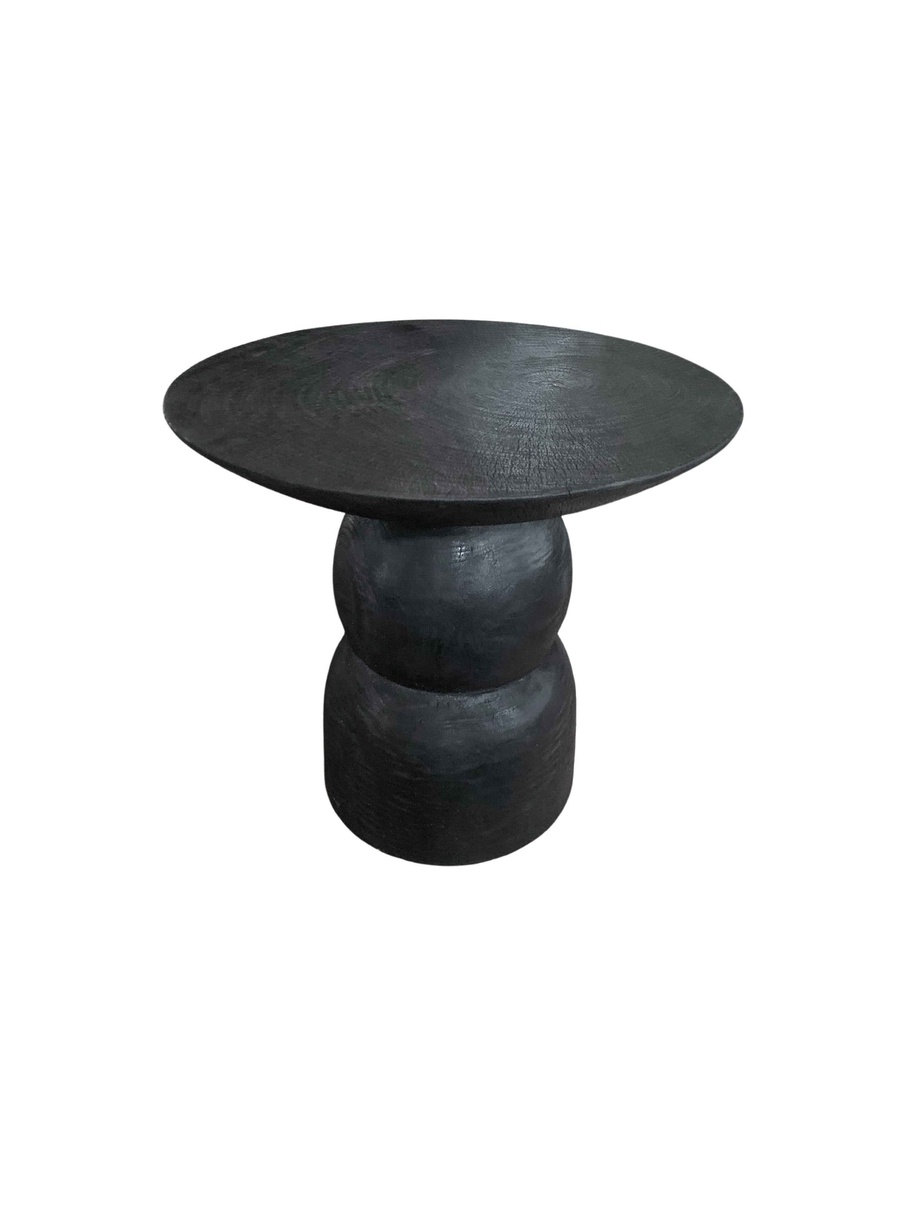 A wonderfully organic round side table. Its rich black pigment was achieved through burning the wood three times. Its neutral pigment and subtle wood texture makes it perfect for any space. A uniquely sculptural and versatile piece certain to invoke