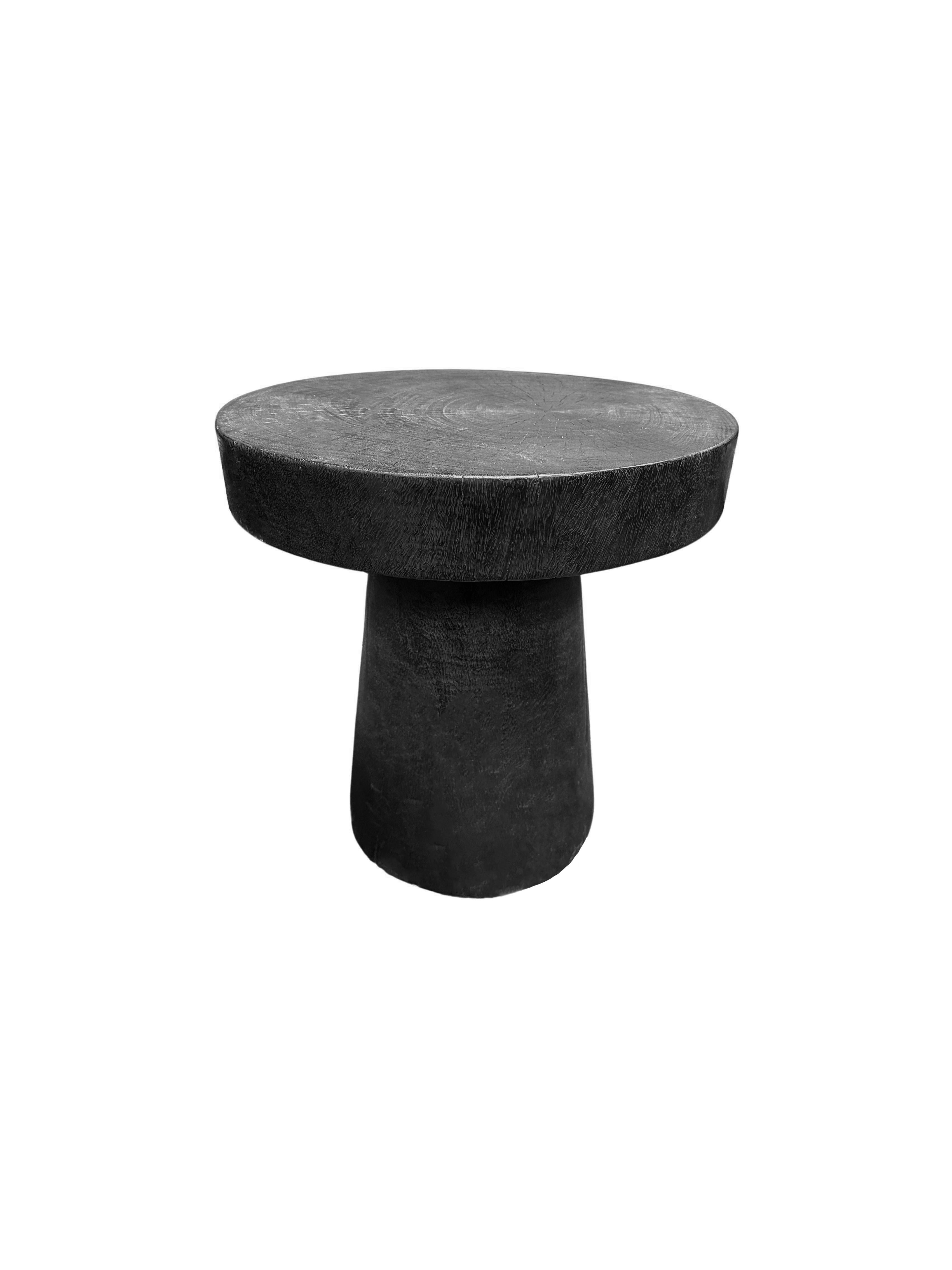 A wonderfully organic round side table. Its pigment was achieved through burning the wood multiple times and finished with a clear coat. Its neutral pigment and subtle wood texture makes it perfect for any space. This table was crafted from mango