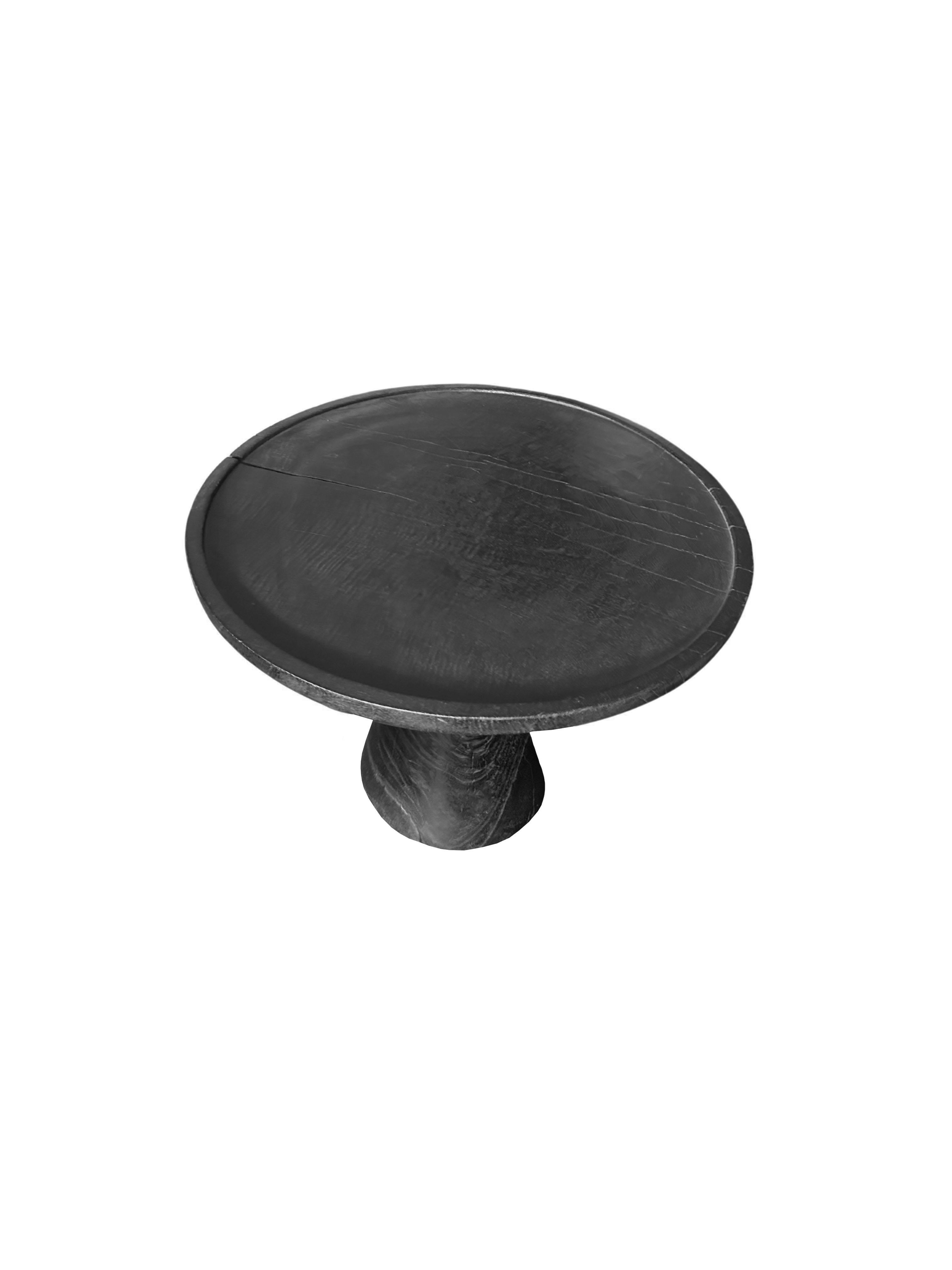 A wonderfully organic round side table. Its rich black pigment was achieved through burning the wood three times. Its neutral pigment and subtle wood texture makes it perfect for any space. A uniquely sculptural and versatile piece. This table was