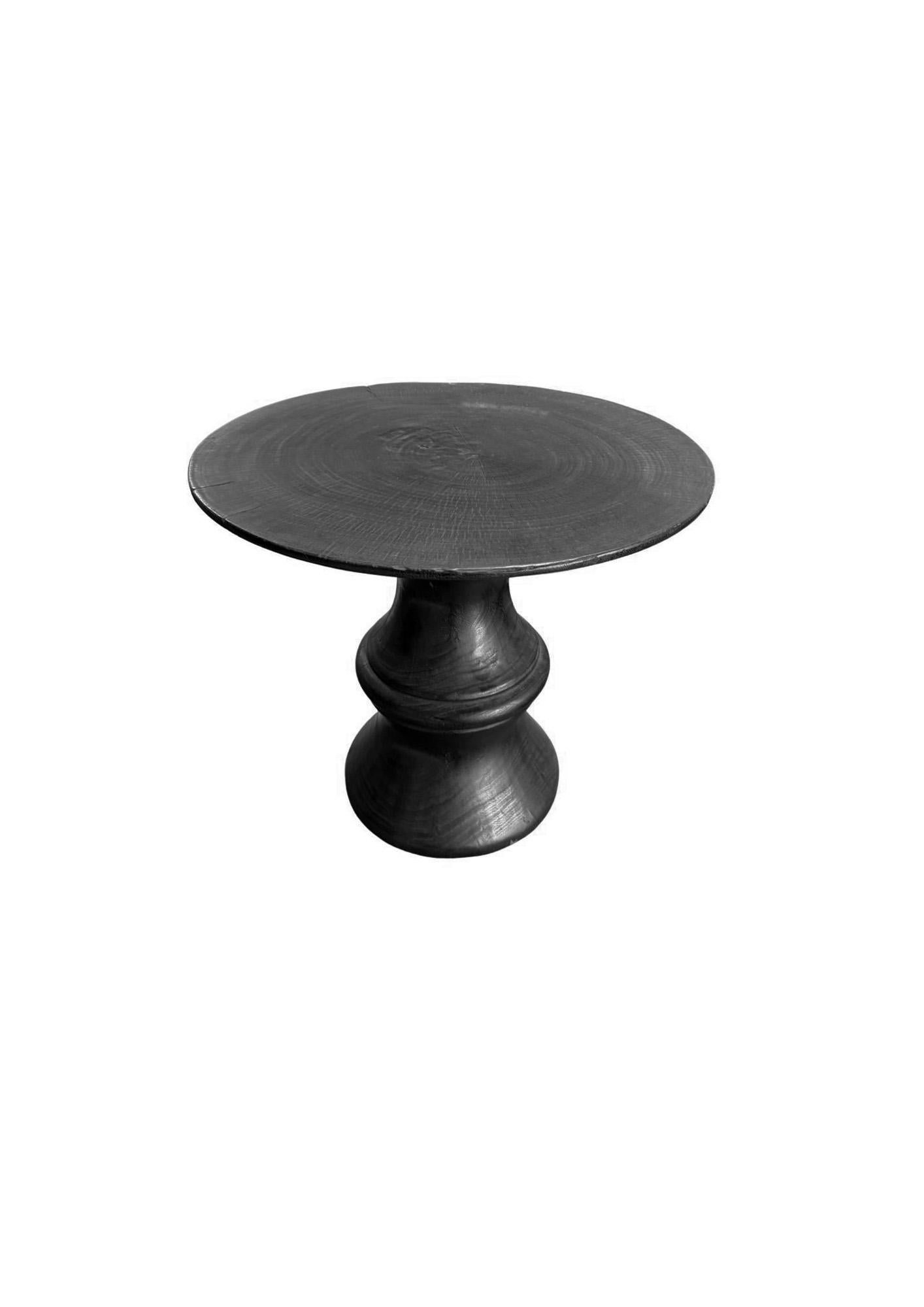 Una mesa auxiliar redonda maravillosamente orgánica. Su pigmentación se consiguió quemando la madera varias veces y se terminó con una capa transparente. Su pigmento neutro y su sutil textura de madera lo hacen perfecto para cualquier espacio. Esta