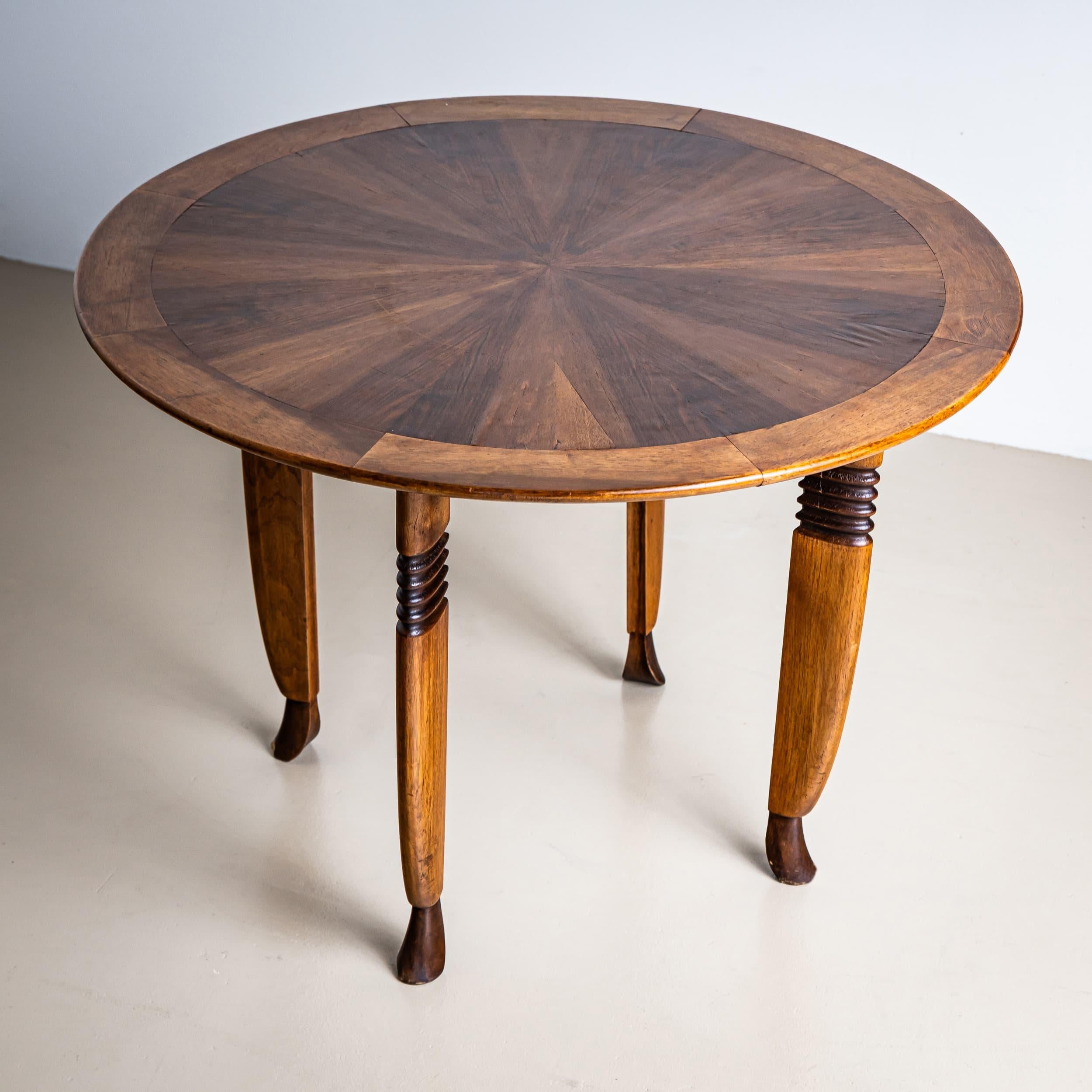 Round side table featuring uniquely designed legs with fluted detailing and slightly recessed feet. The tabletop is radially veneered, highlighting its fine craftsmanship. The table remains in its original, unrestored condition.