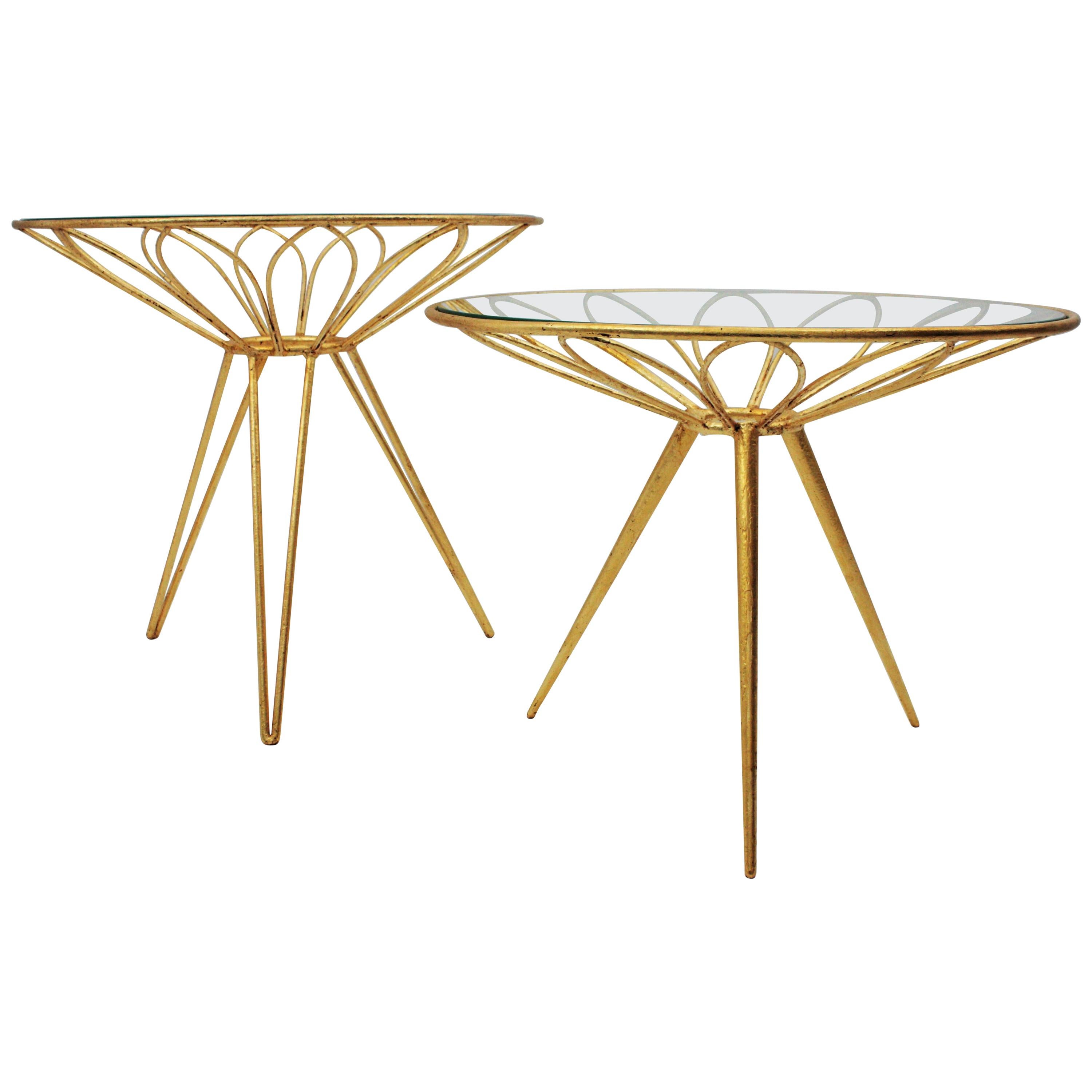 Set of two Midcentury Hollywood Regency daisy flower gilt iron coffee tables, France, 1950s.
A set of two glamorous gold leaf gilt iron occasional tables with glass round tops standing on tripod bases.
These tables are very similar in design. The