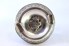 Round silver ashtray with central arms, frieze, and filled base