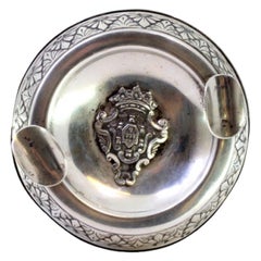 Round silver ashtray with central arms, frieze, and filled base