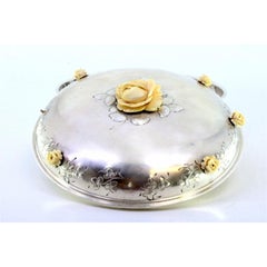 Round silver candy box with floral reliefs on the lid and flower-shaped handle